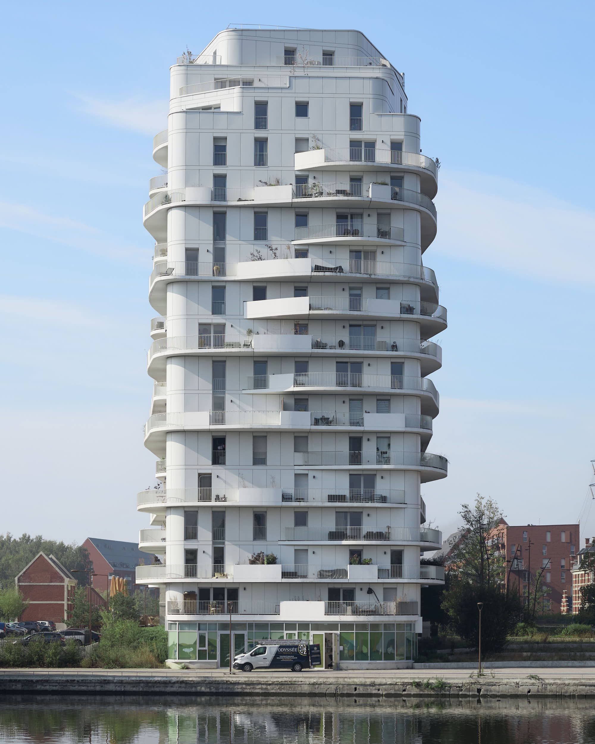 Vue du haut et de la façade de l'immeuble Brooklyn Tower à Marquette-lez-Lille, isolé par un ciel bleu peu nuageux.