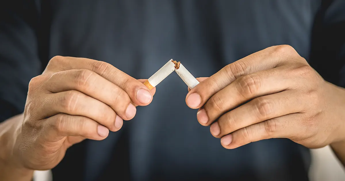 A man breaks a cigarette in two.