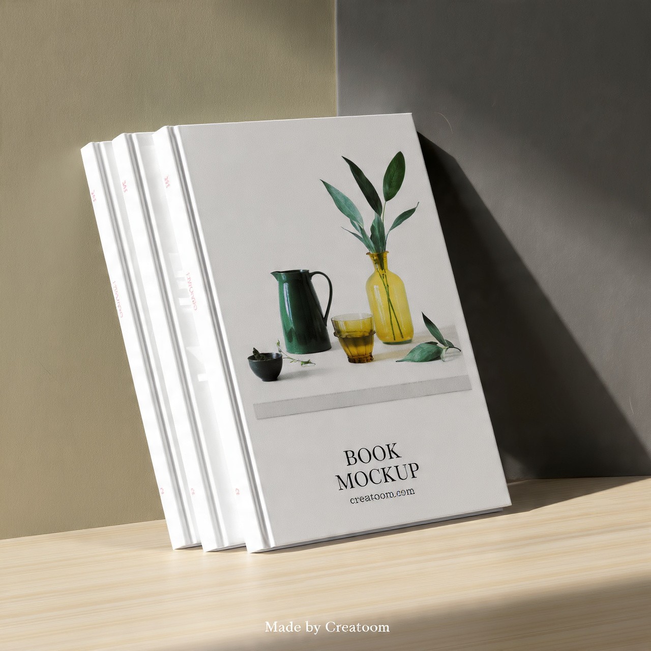 Two white book mockups leaning against a mint green and black wall.