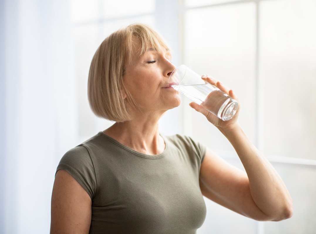 thirsty woman drinking water after using a sauna for help to lose weight