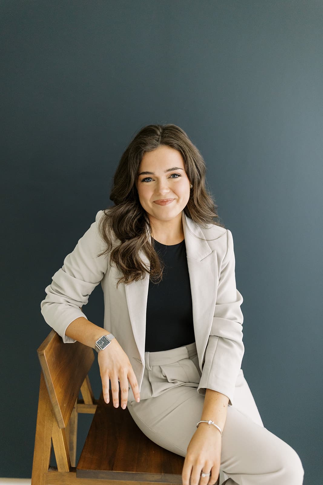 A model in a beige suit poses confidently while seated at Revelator Studio in Shreveport, photographed by Andy Roberts, showcasing the studio’s natural light and sleek, professional atmosphere.