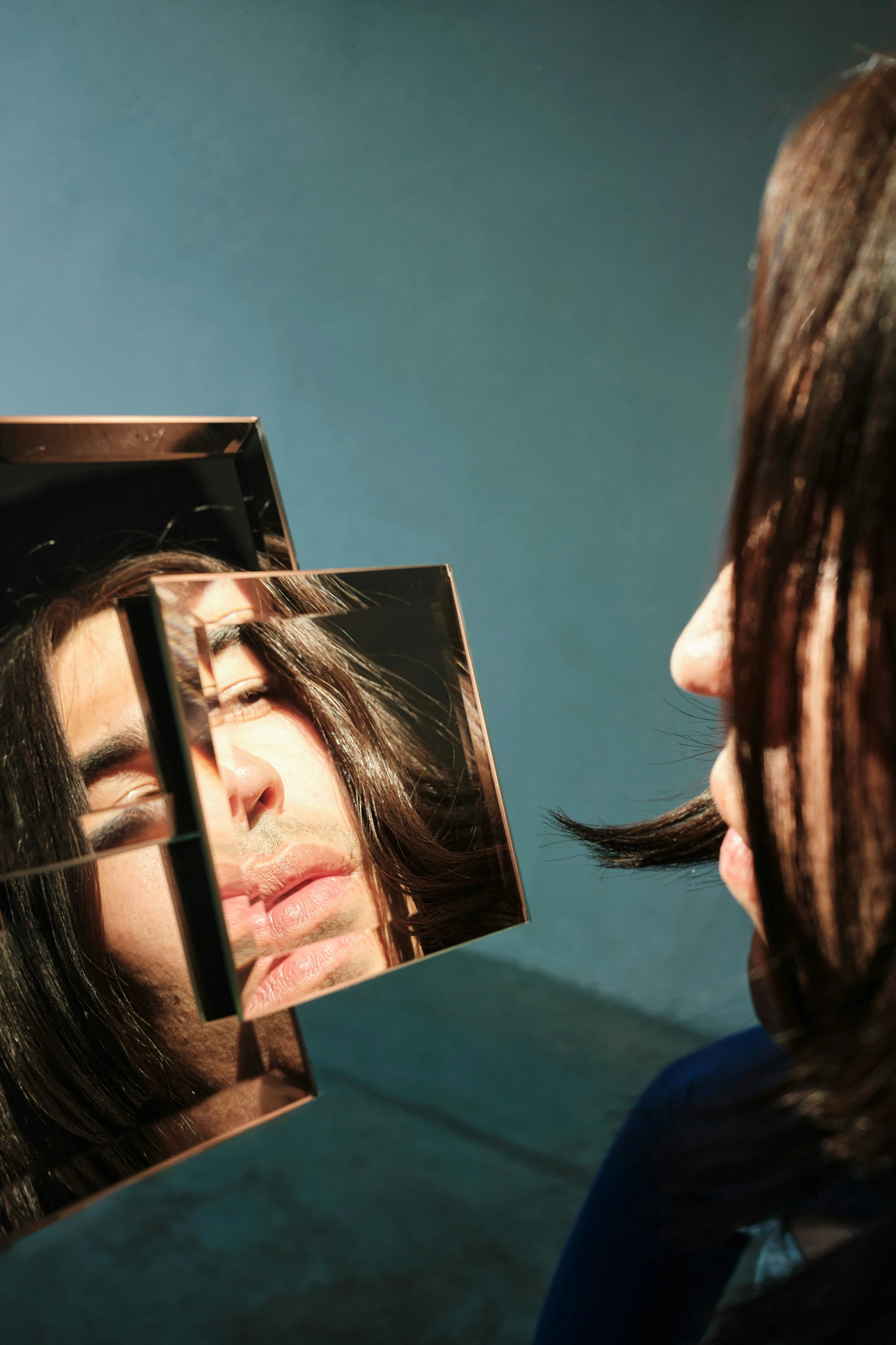 Person looking into a fragmented mirror that reflects distorted parts of their face, symbolizing body image concerns, self-perception, and identity.