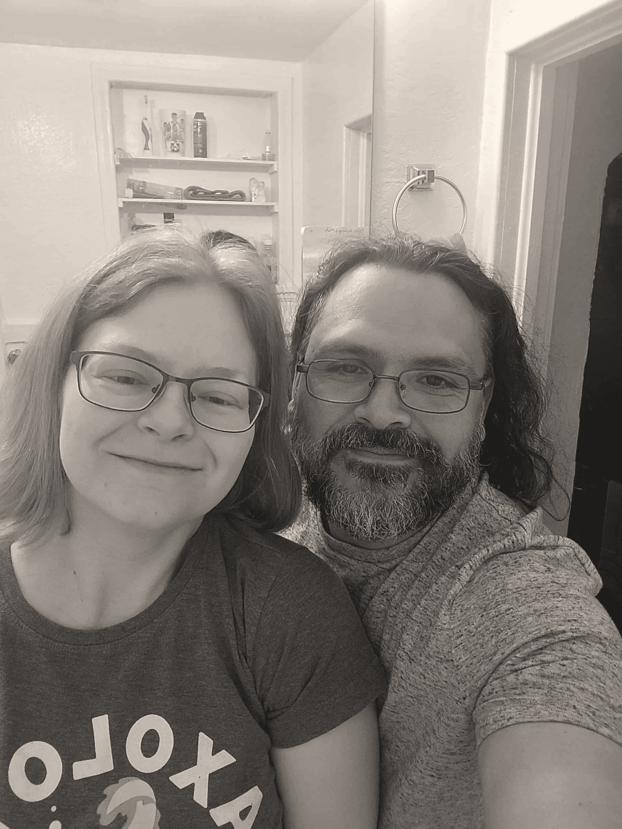 Selfie of a smiling couple, both wearing glasses. The woman has short hair, and the man has a beard. Chad Hintze Handyman.