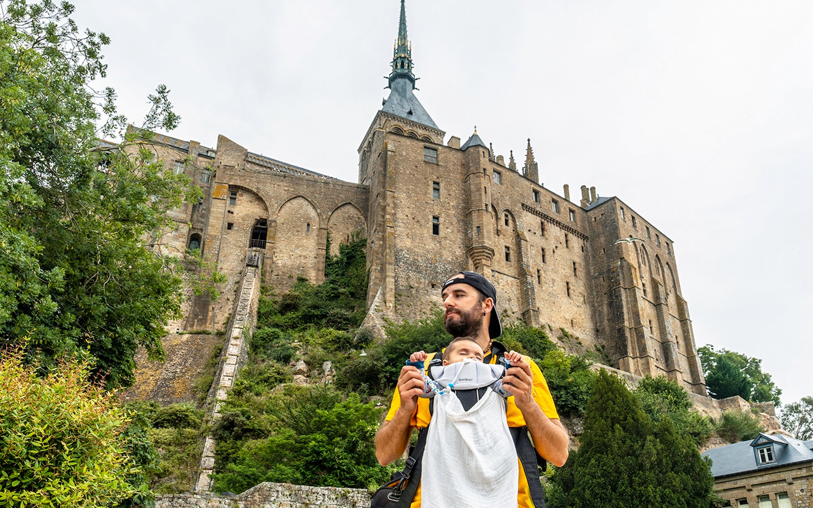 父亲带着背带里的婴儿参观法国的圣米歇尔山修道院。