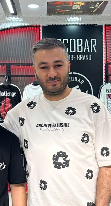 Close-up portrait of a blonde woman in translucent pink glasses and a white shirt on a soft blue background.
