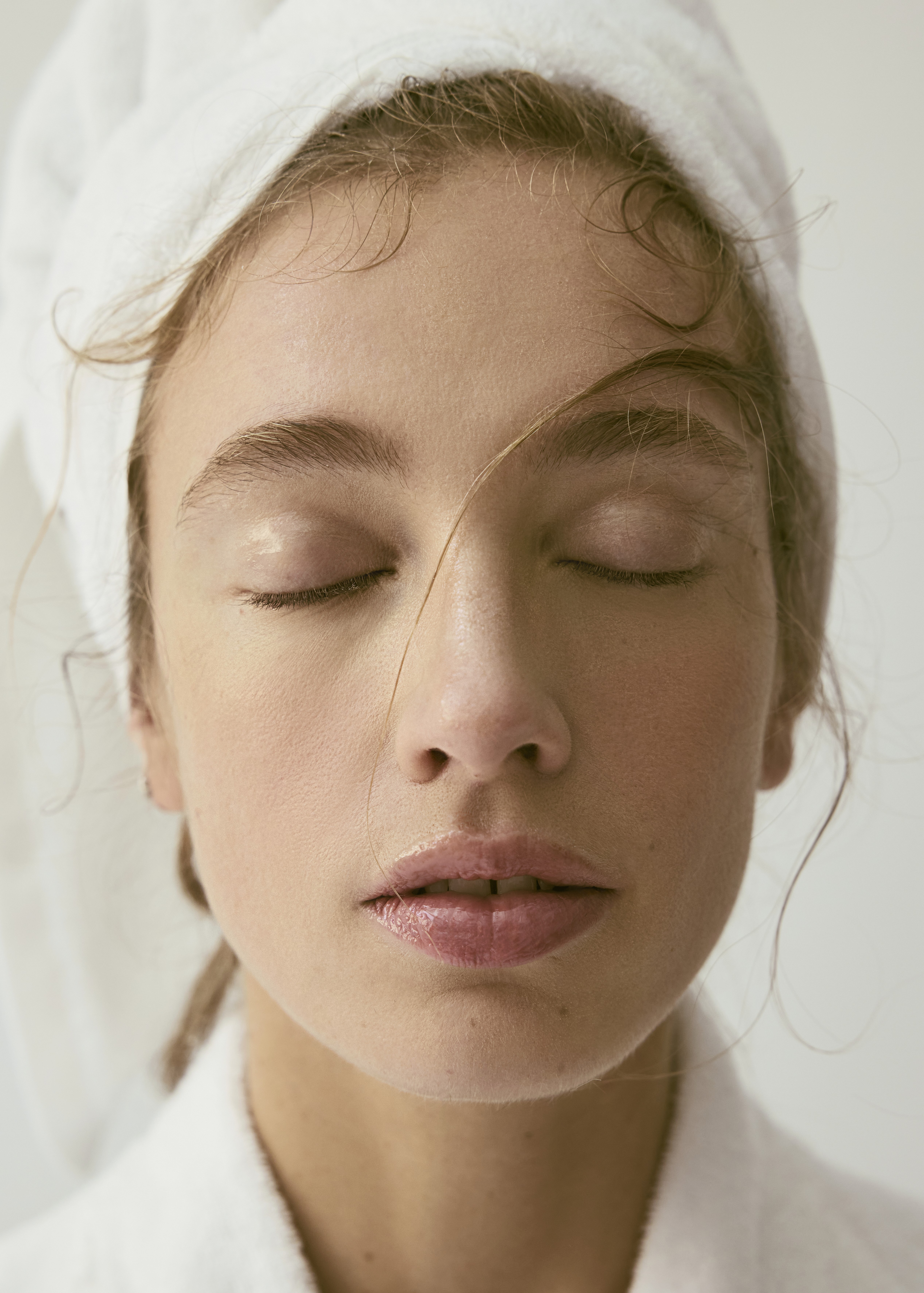Gros plan du visage d’une femme aux yeux fermés, en lumière douce, avec une serviette blanche