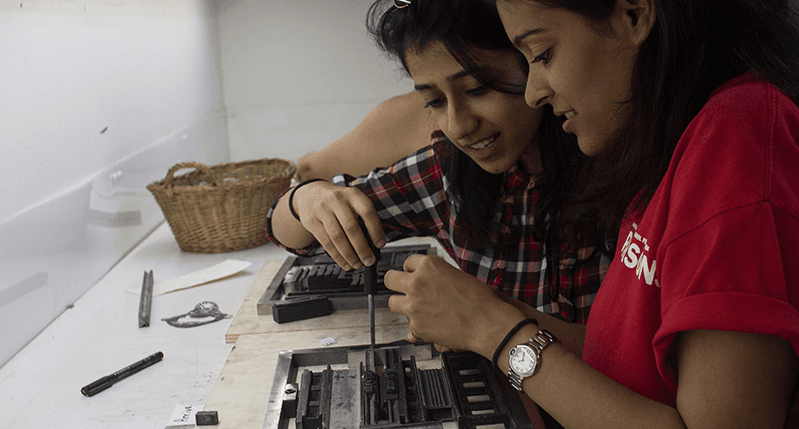 students looking at metal press
