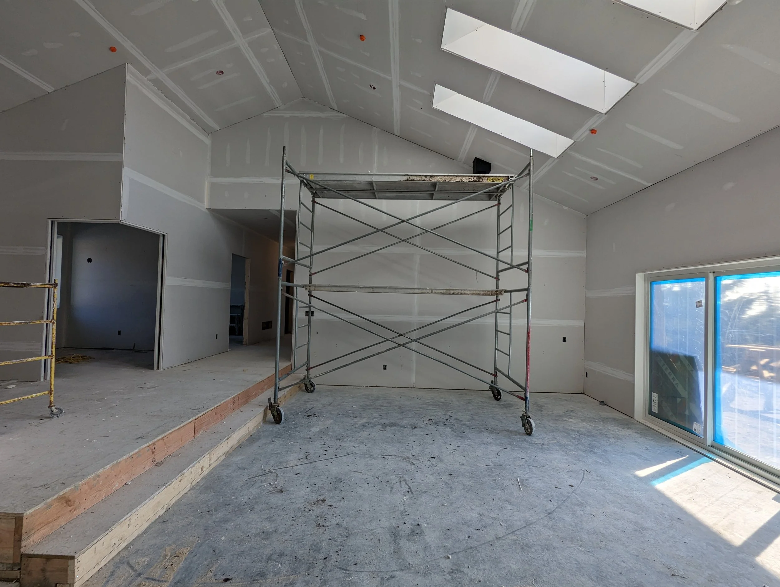 Modern two-story home with large glass windows, warmly lit interiors, and a balcony. Surrounded by trees and a manicured lawn at dusk. Cozy ambiance.