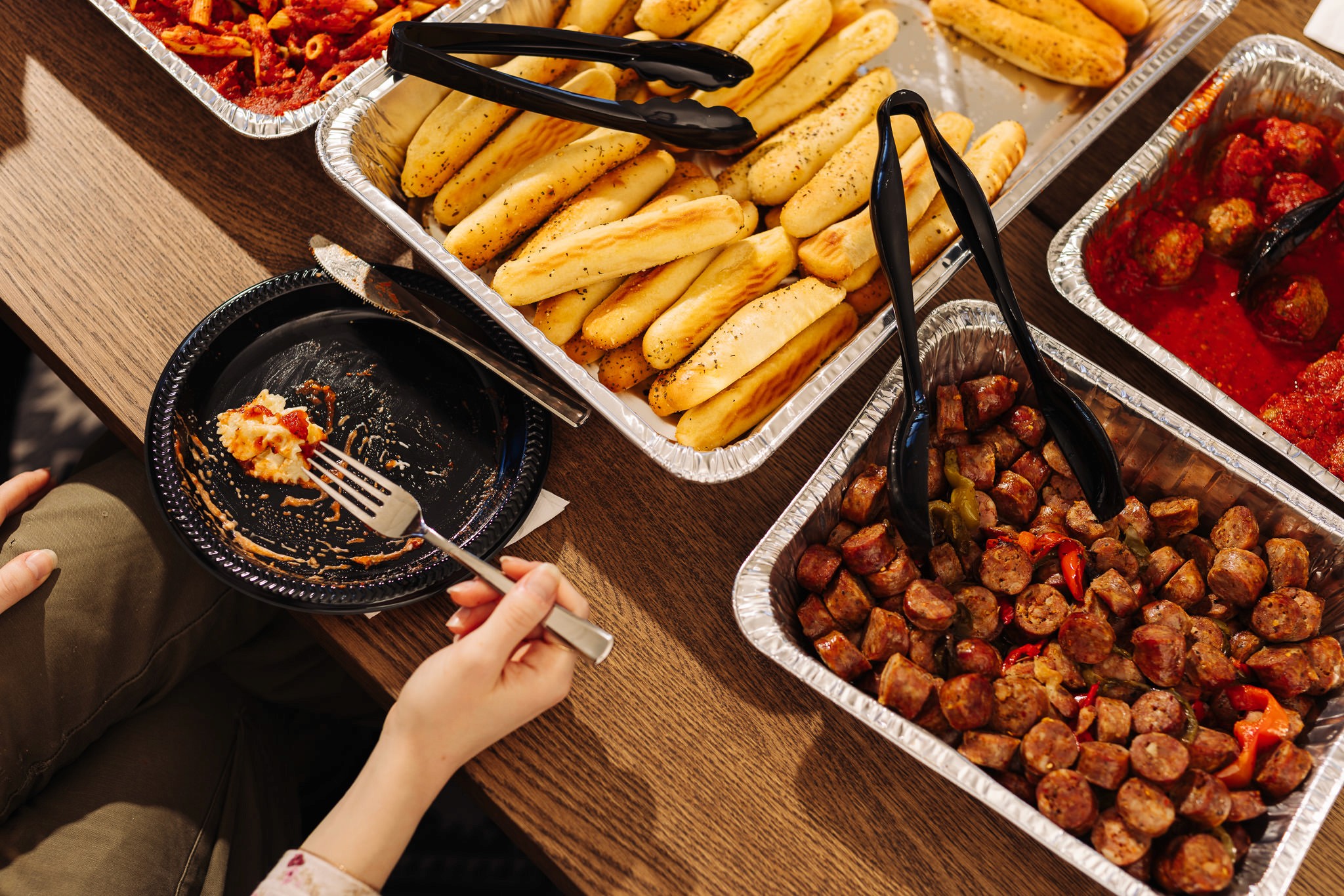 top-down shot showing italian catering with someone's hand and fork in process of eating the food
