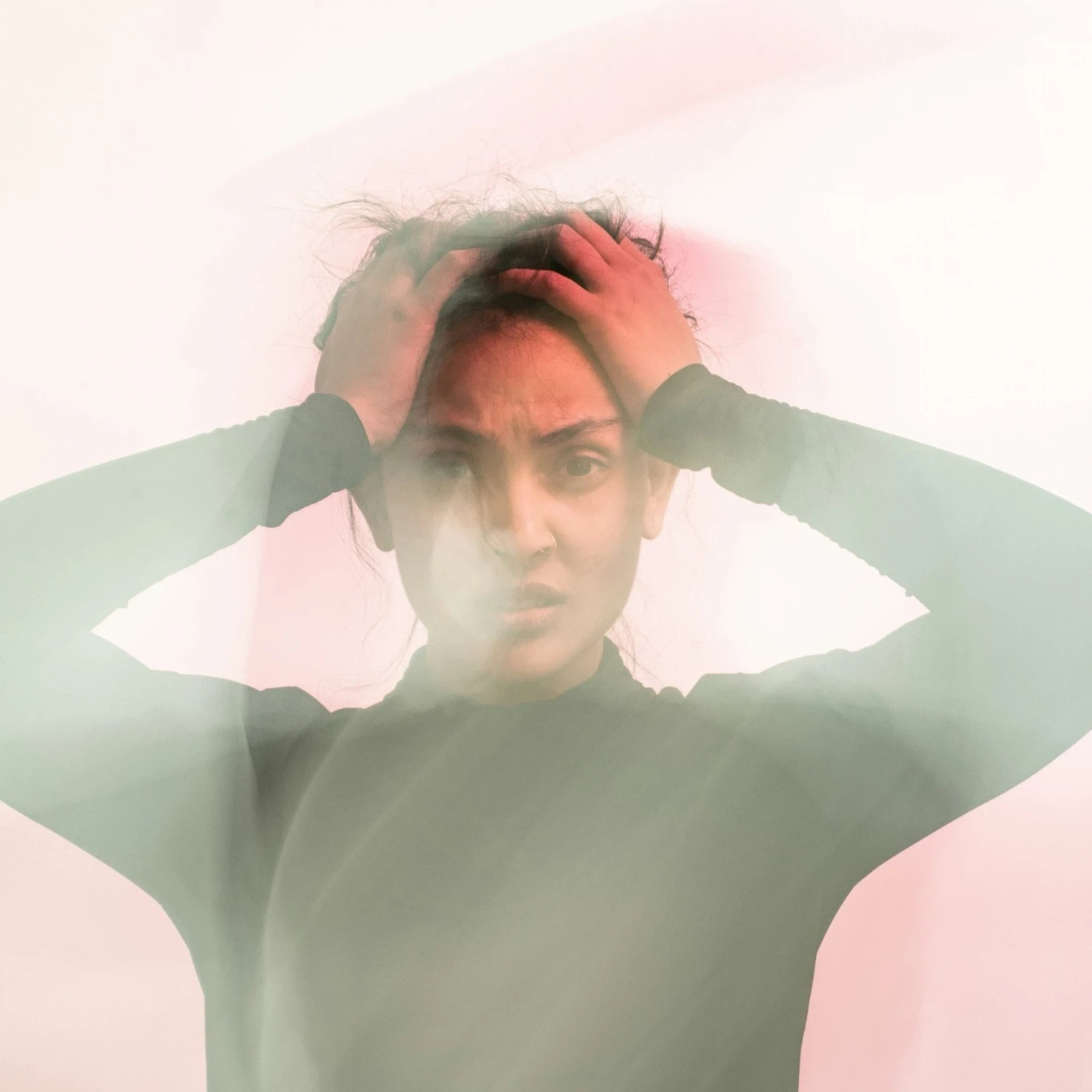 Stressed woman holding her head with blurred double exposure effect, symbolizing anxiety and the need for therapy in Los Angeles.