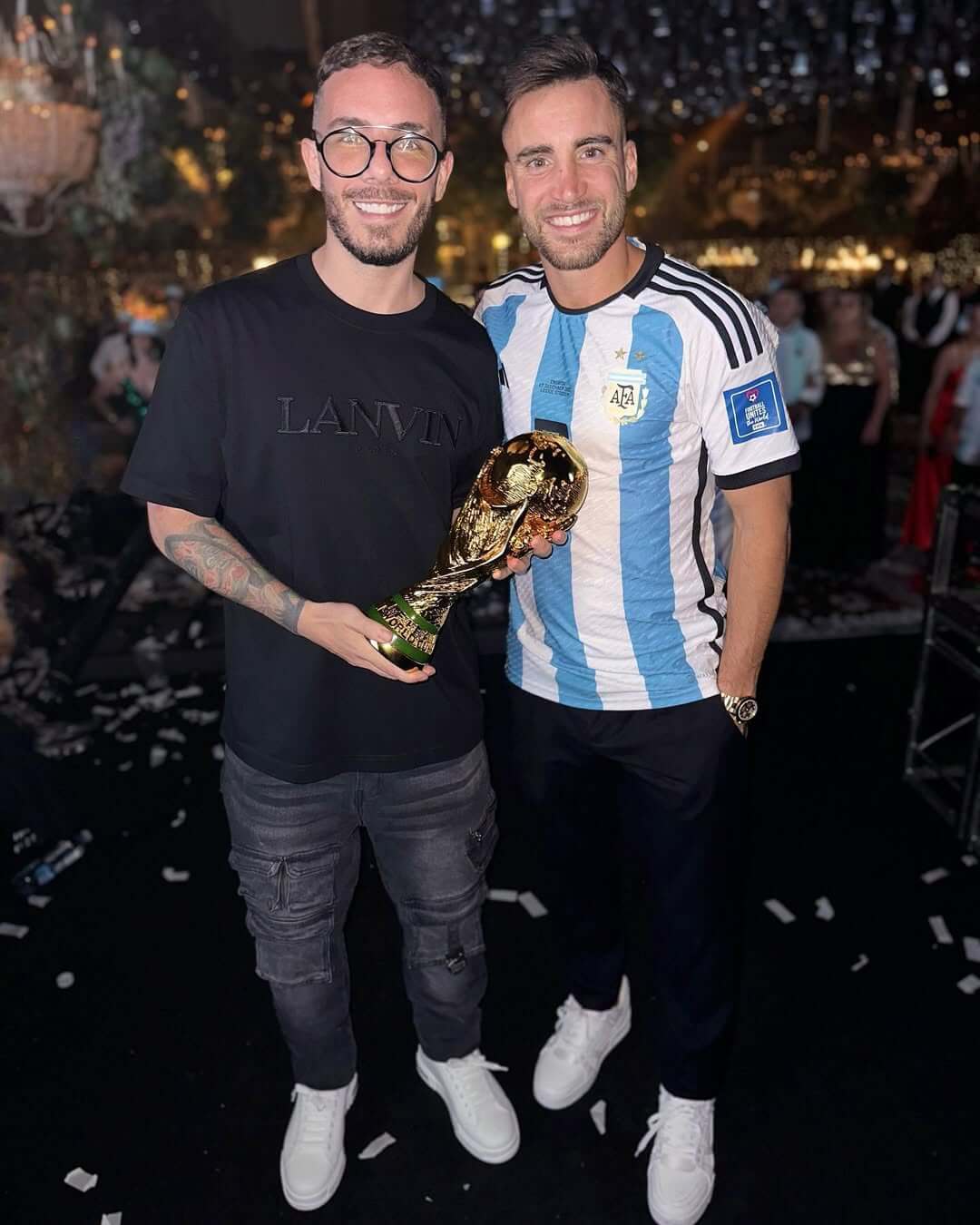 Fer Palacio con Tagliafico sosteniendo el trofeo del Mundial en un evento nocturno.