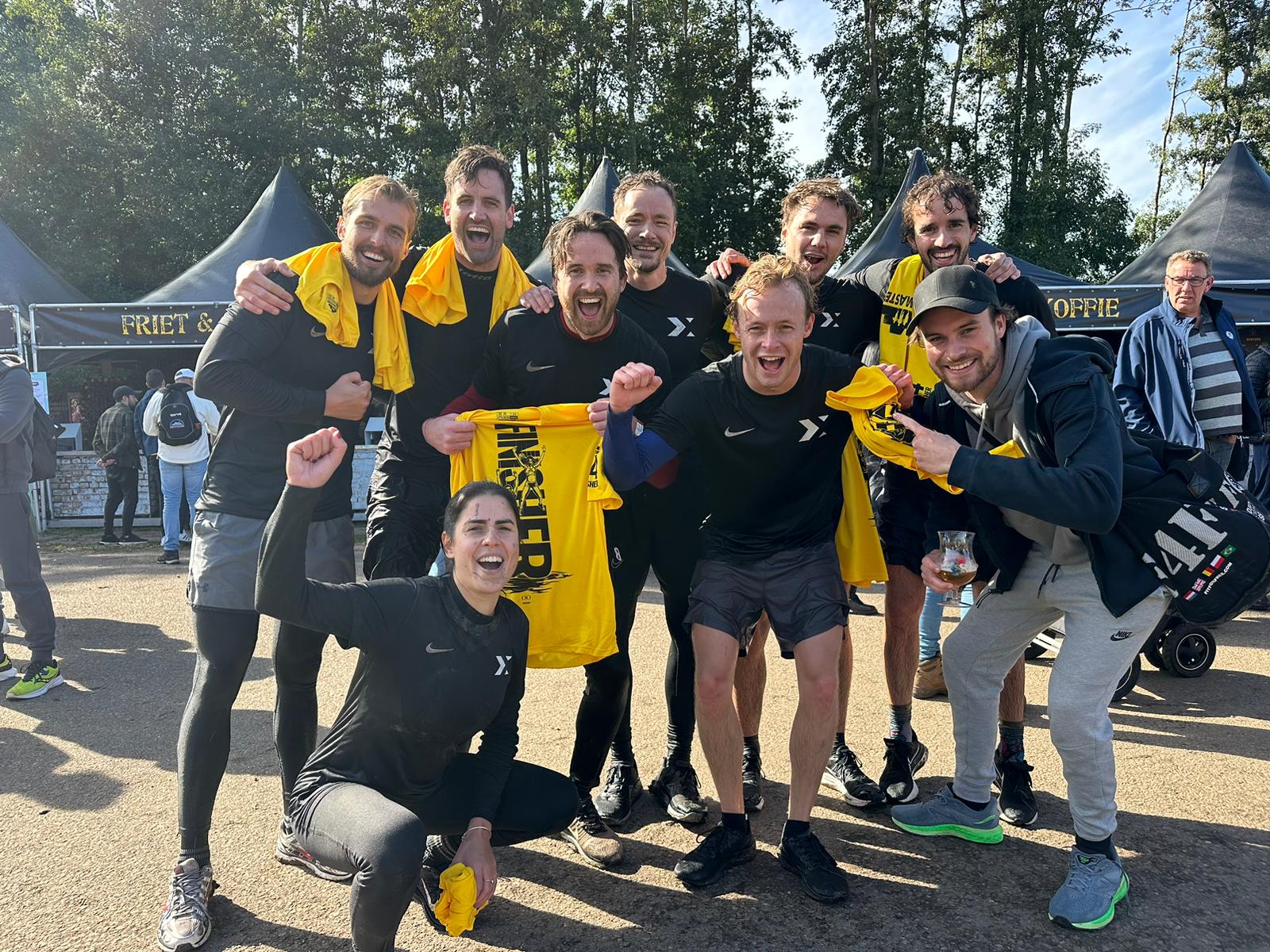 A group of people in yellow and black outfits posing joyfully outdoors, with trees in the background.