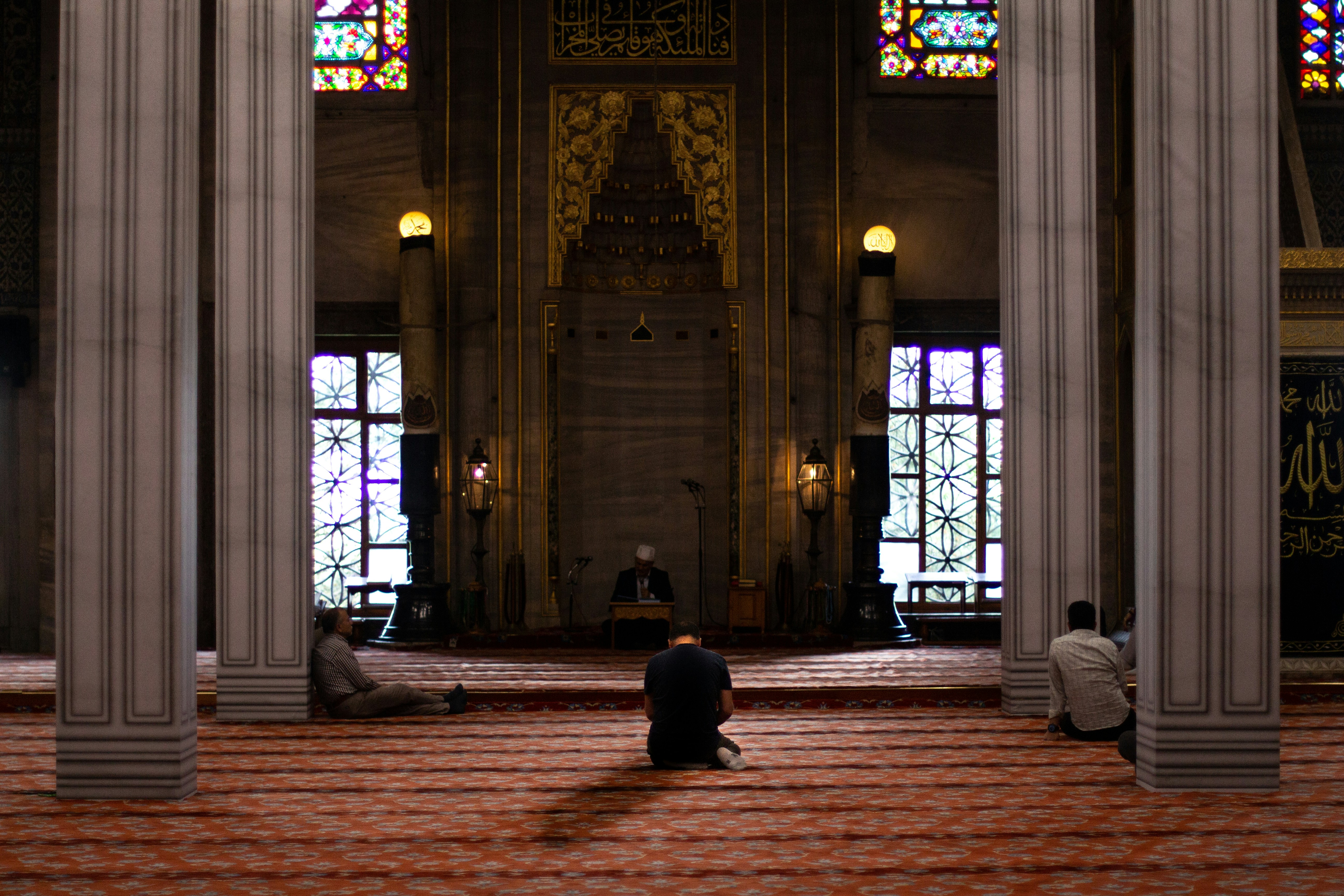 three men sitting inside mosque