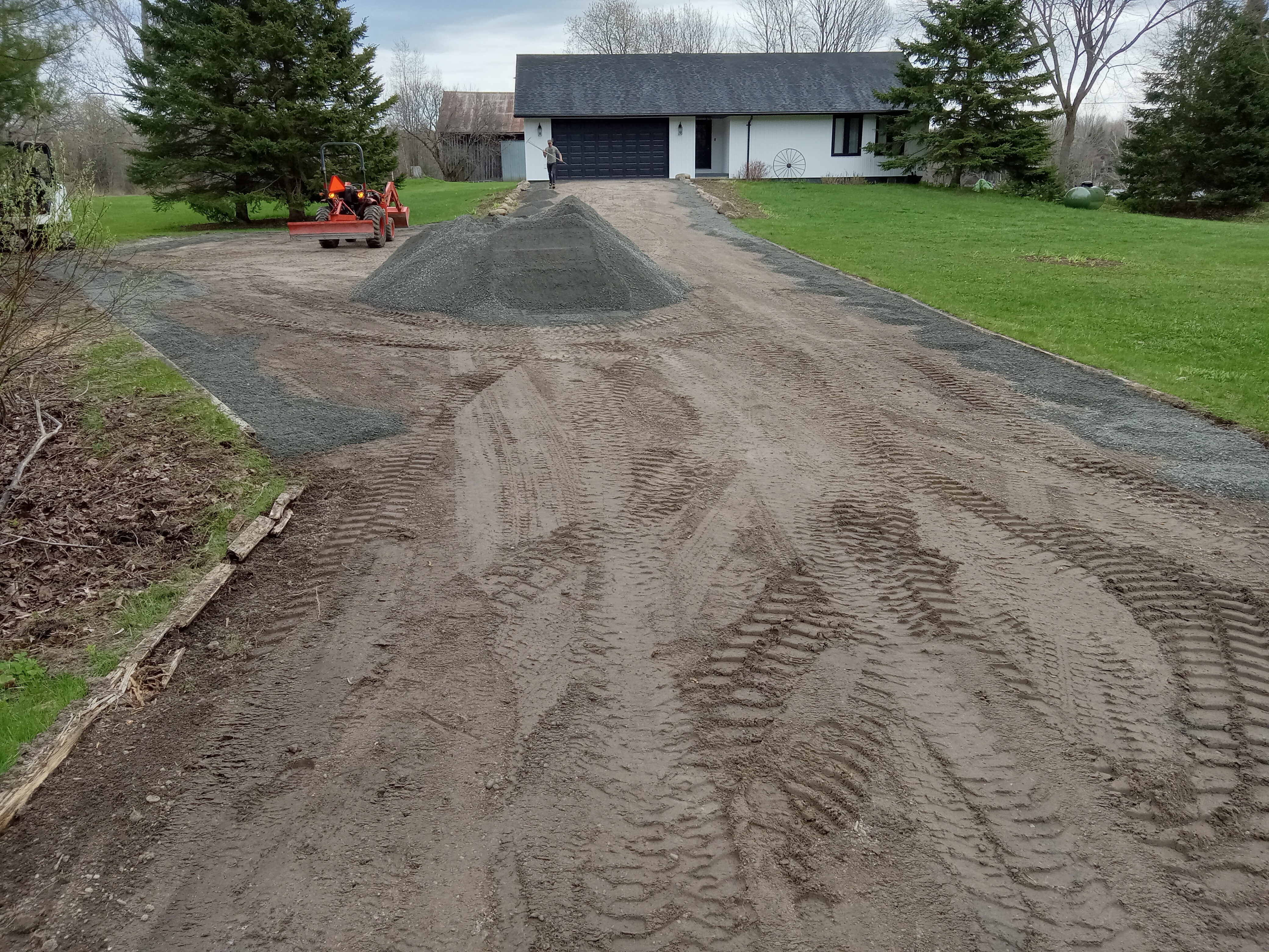 Gravel driveway being reshaped after excess material was removed to establish proper drainage.