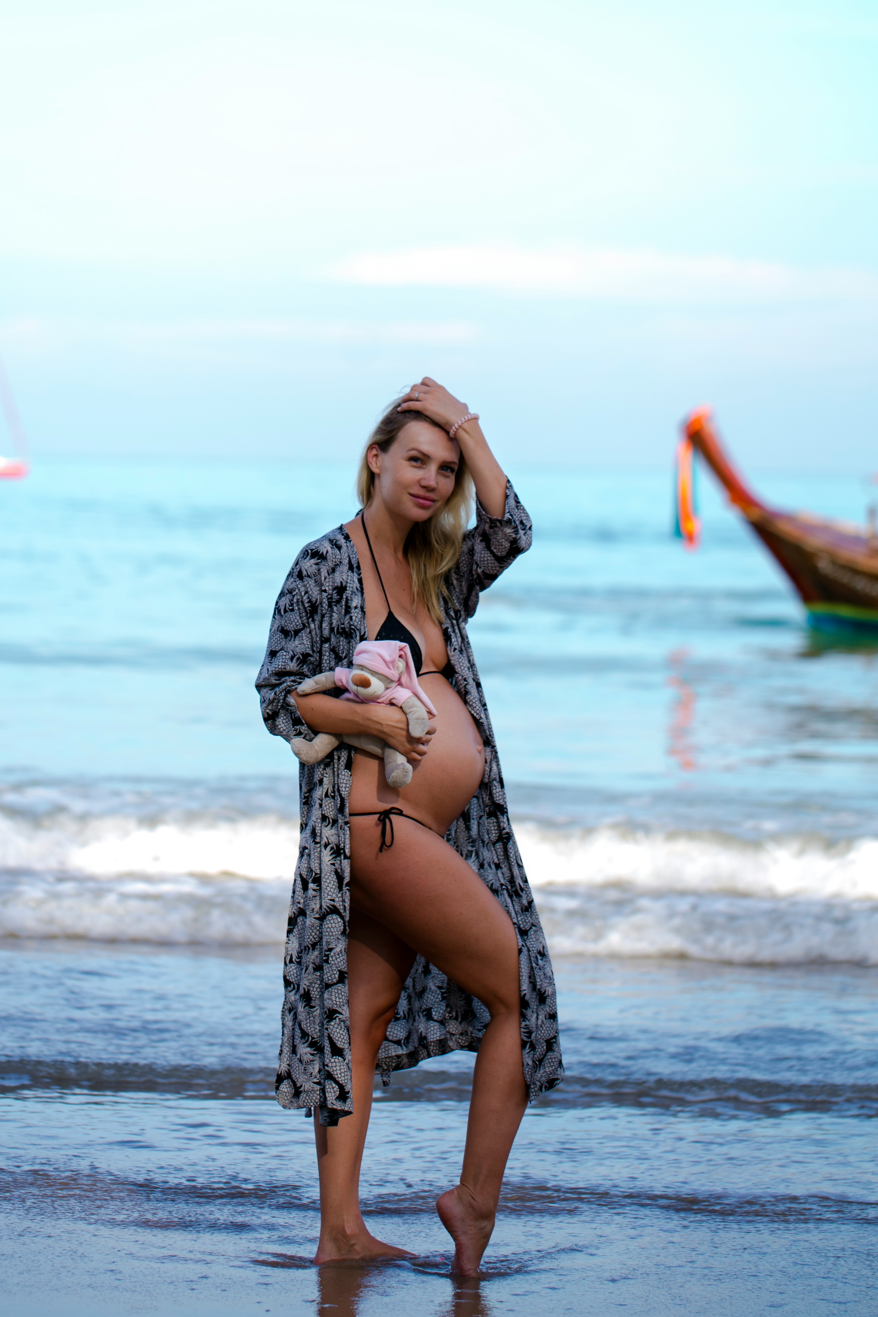 a person in a dress holding a stuffed animal on a beach