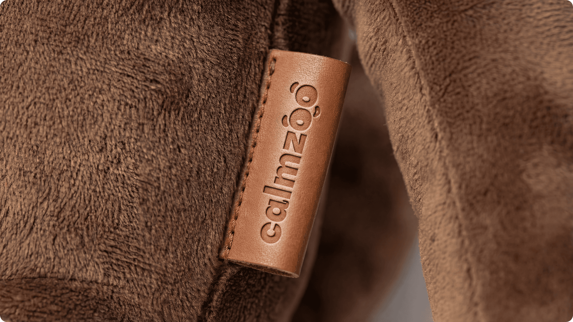 Portrait of a woman with curly hair wearing a two-tone gray and orange beanie against a neutral background.