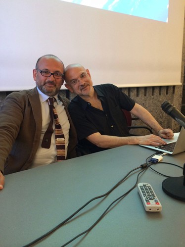 A photo of two people sitting at a conference table in front of a laptop.
