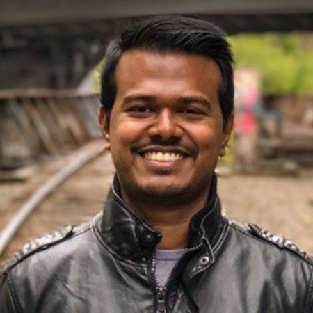 Close-up portrait of Jason smiling outdoors, wearing a stylish jacket.