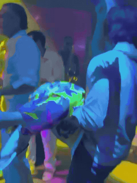 A couple dances closely, showcasing a flowing green dress, against a soft, blurred background of other guests.