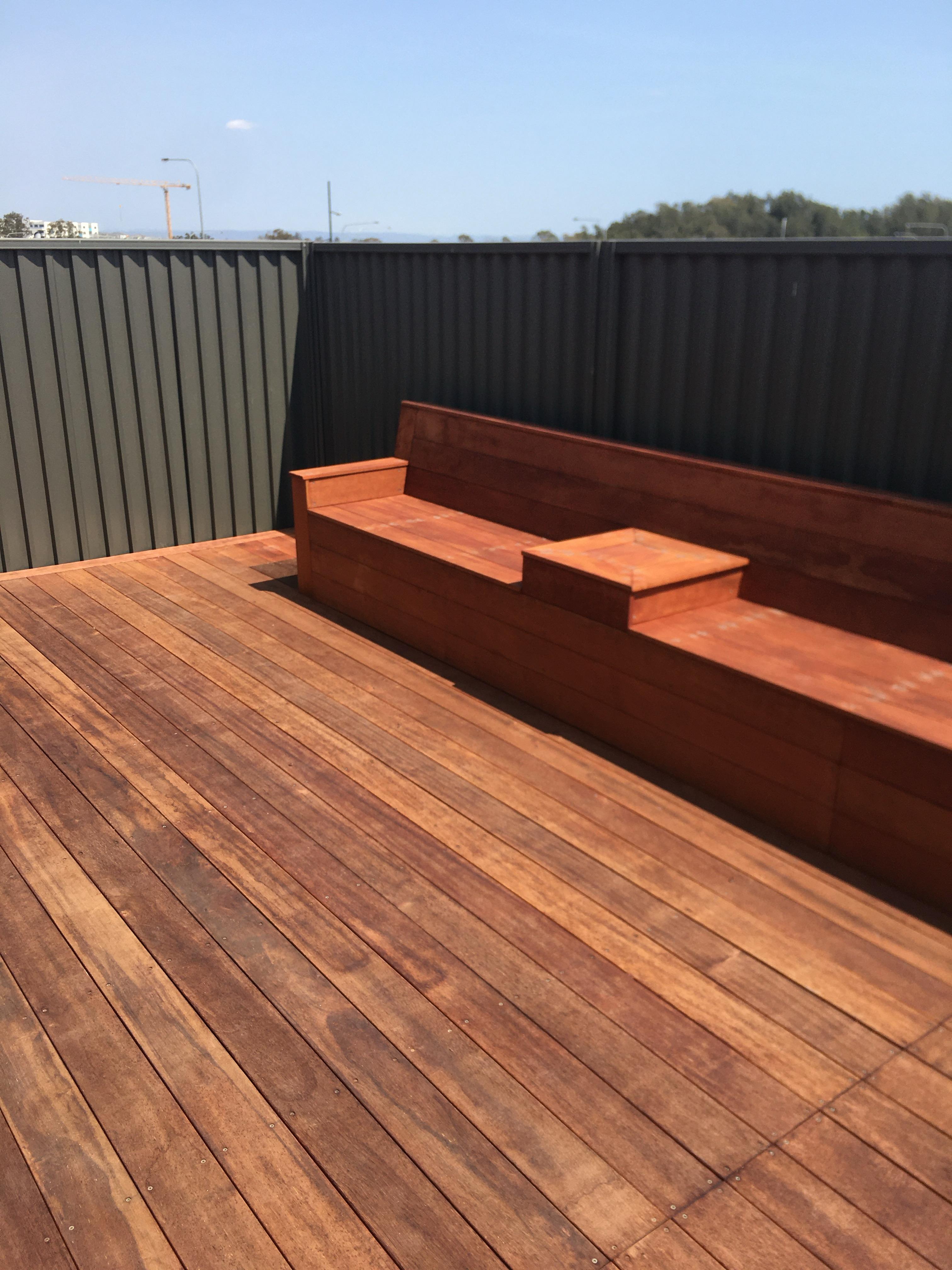 A wooden deck features a modern seating area against a simple backdrop, under clear blue skies.