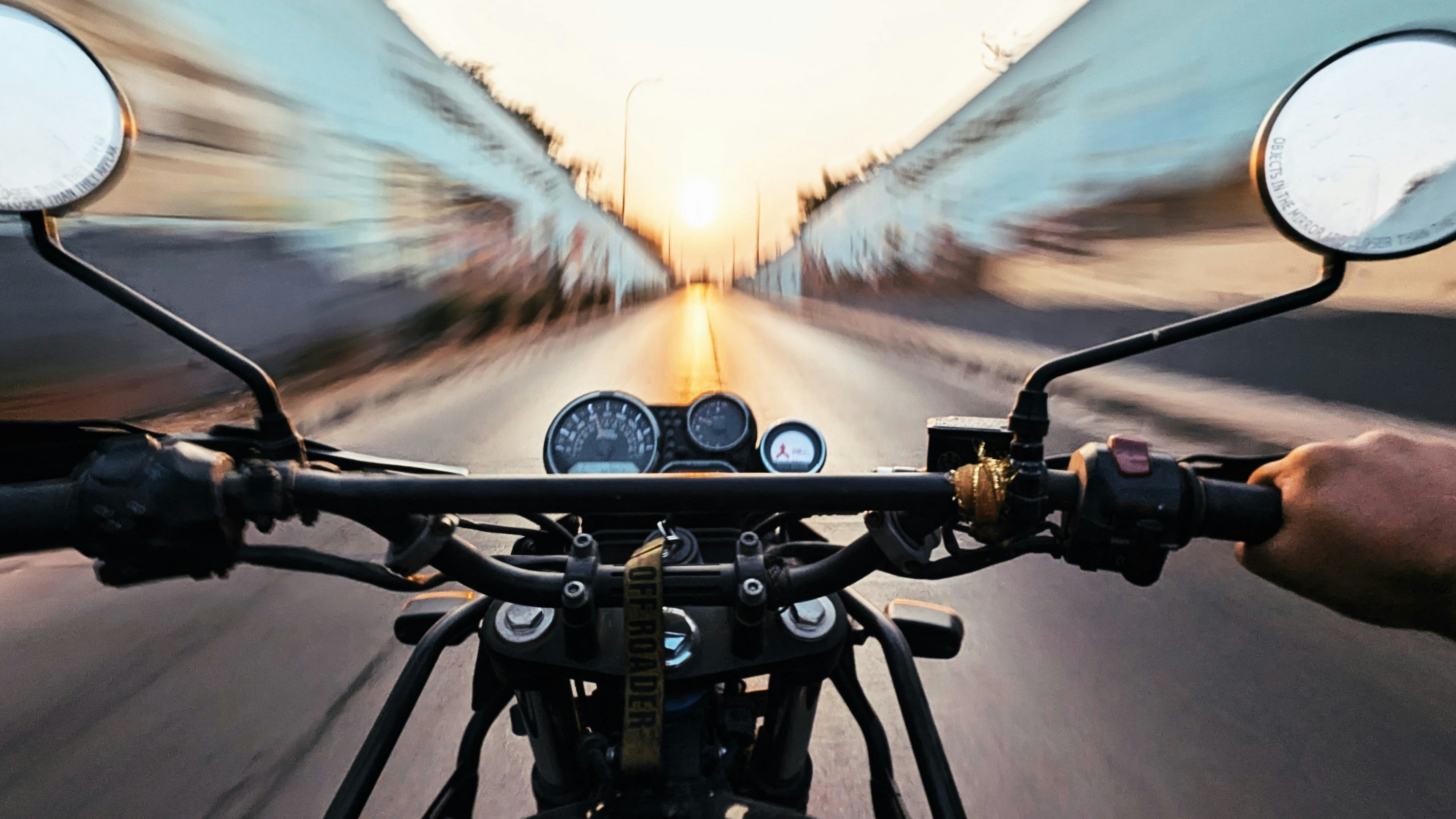 Riding a motorcycle down a road at sunset