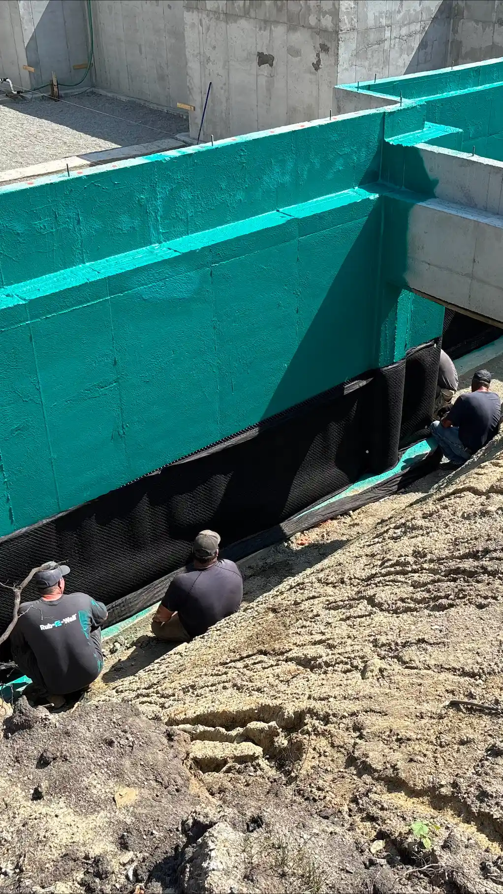 Une nouvelle construction de maison avec l'étanchéité Rub-R-Wall Aqua et trois applicateurs d'étanchéité