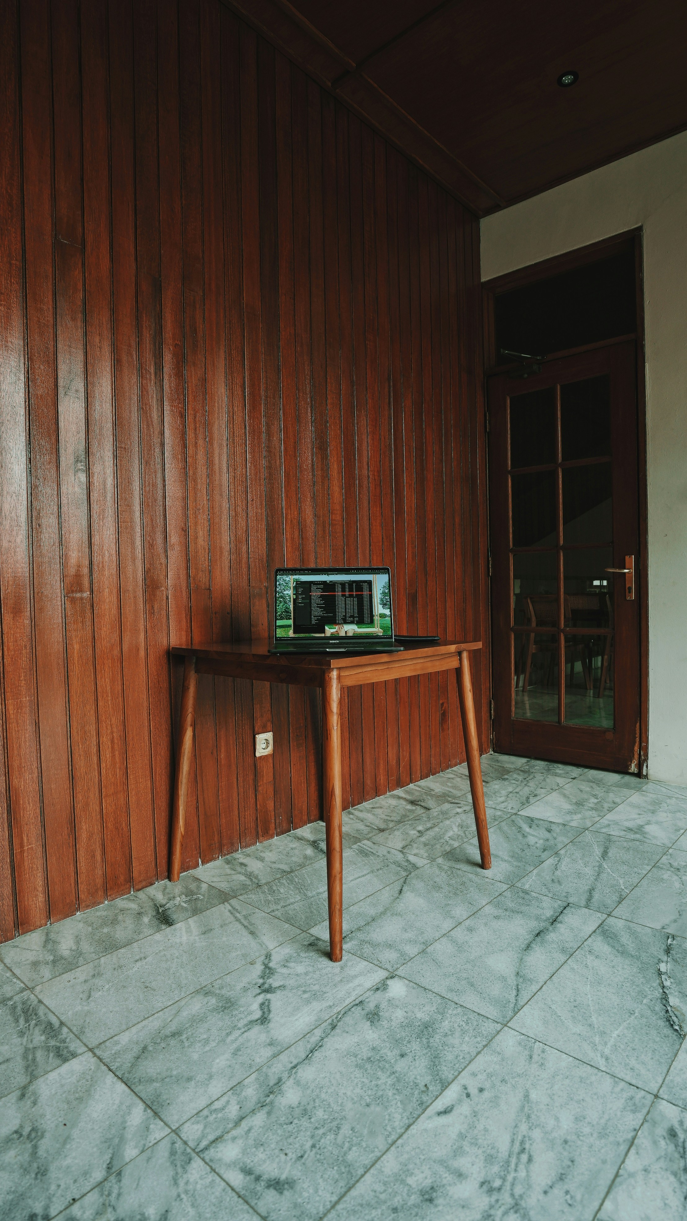 Laptop on a table in an old wood-paneled room.