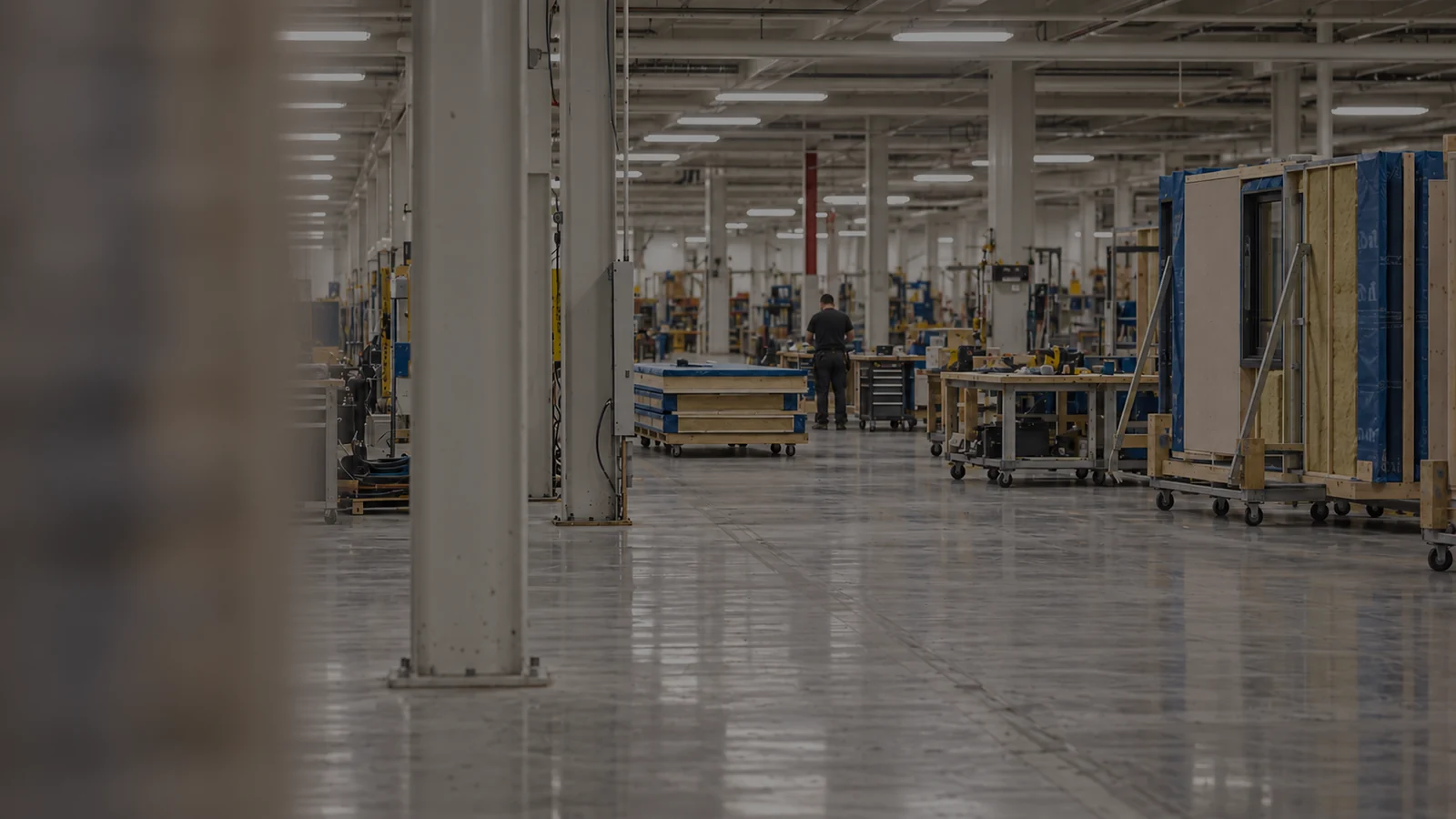 Interior of the empty Therm-O-Disc plant: a long concrete factory floor with structural columns, overhead lighting and idle workbenches