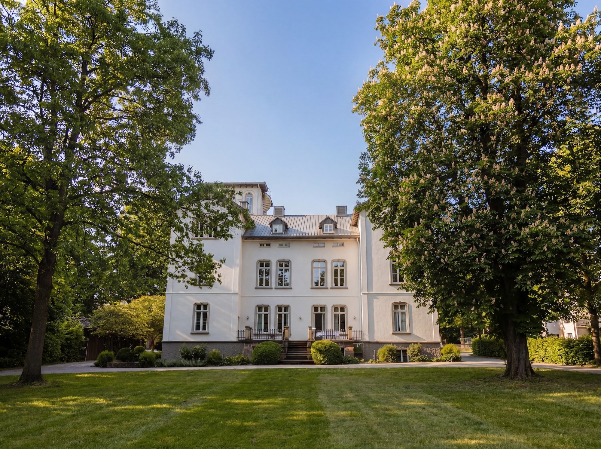 Weiße Villa Kreuztal mit grauem Dach, umgeben von Bäumen, aus der Vogelperspektive