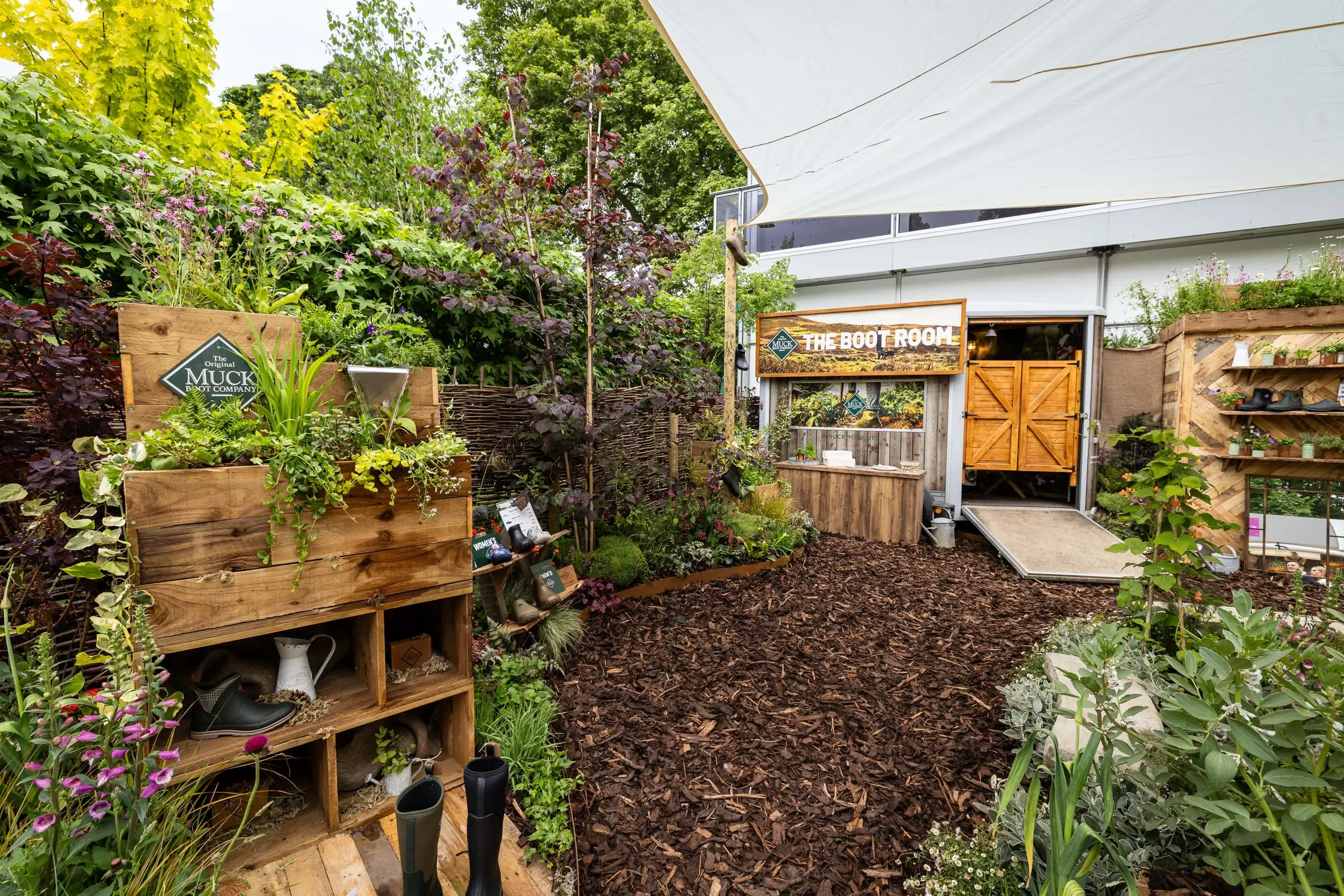 A vibrant garden featuring diverse foliage, wooden structures, and a serene outdoor atmosphere.