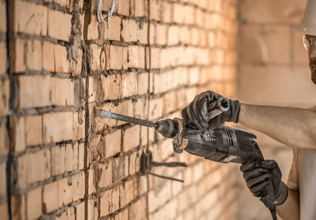 Maçon travaillant sur un mur de briques à l’aide d’une truelle et de mortier.