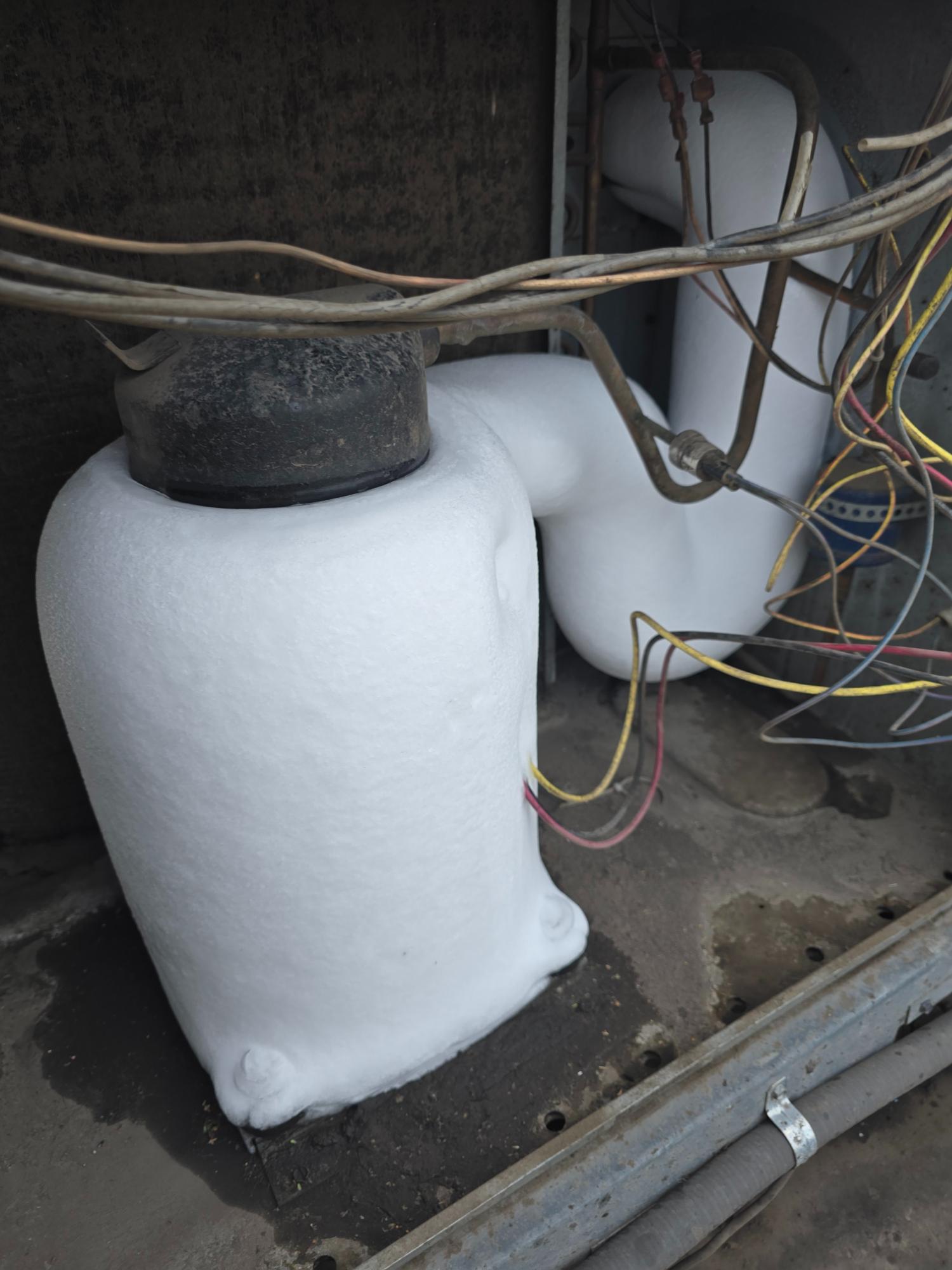 Frozen HVAC compressor covered in ice buildup.