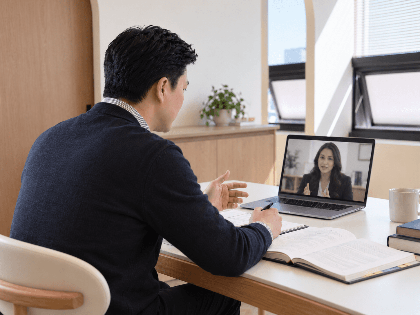 Psychologist speaking with another person by video call at a desk.