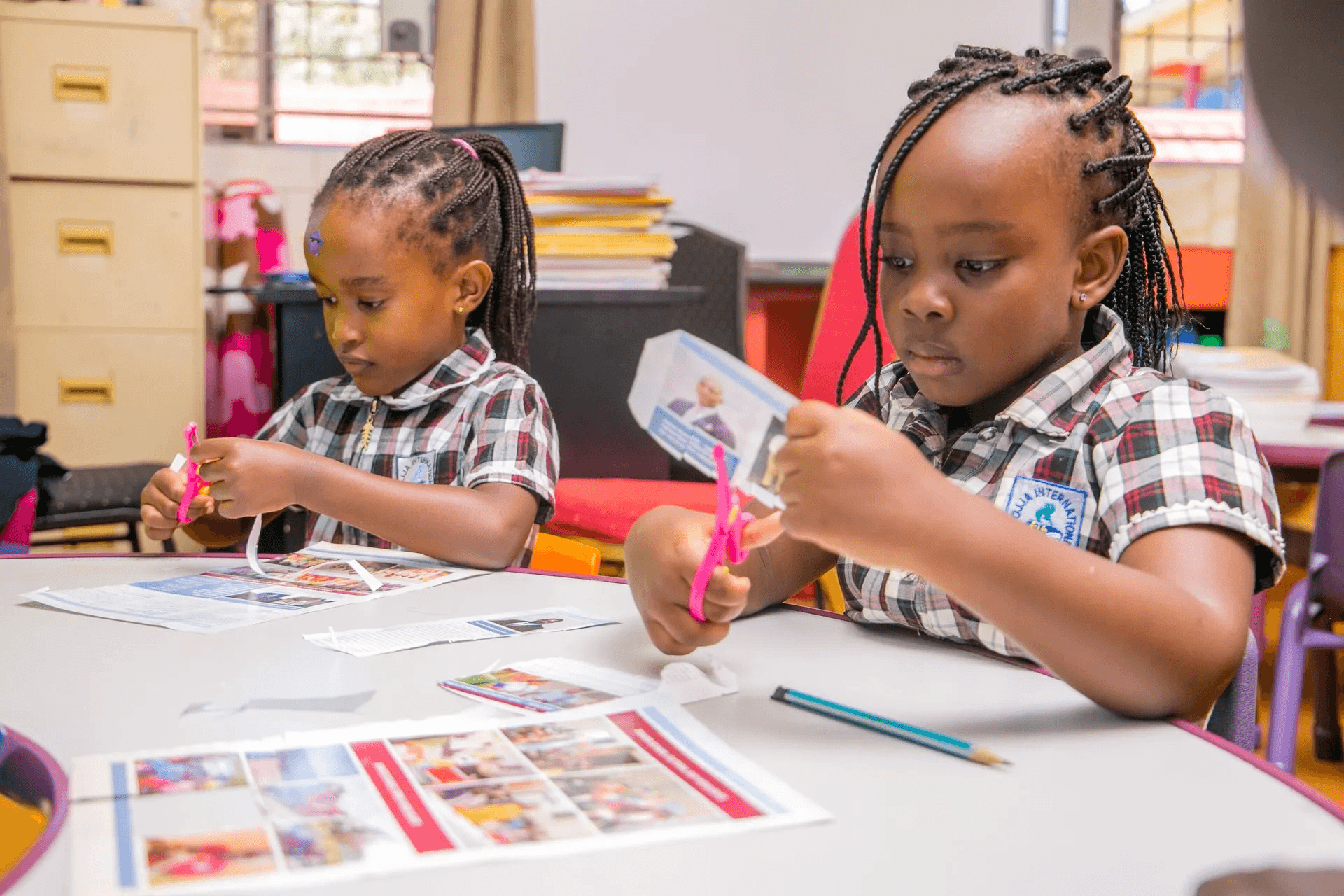 A teacher stands near a whiteboard in a classroom, explaining a lesson to the students.