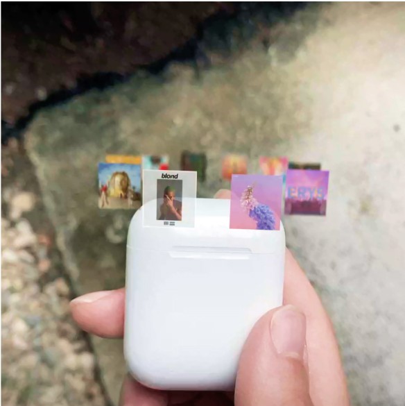 A photo of a hand holding an AirPod case with floating album art hovering above