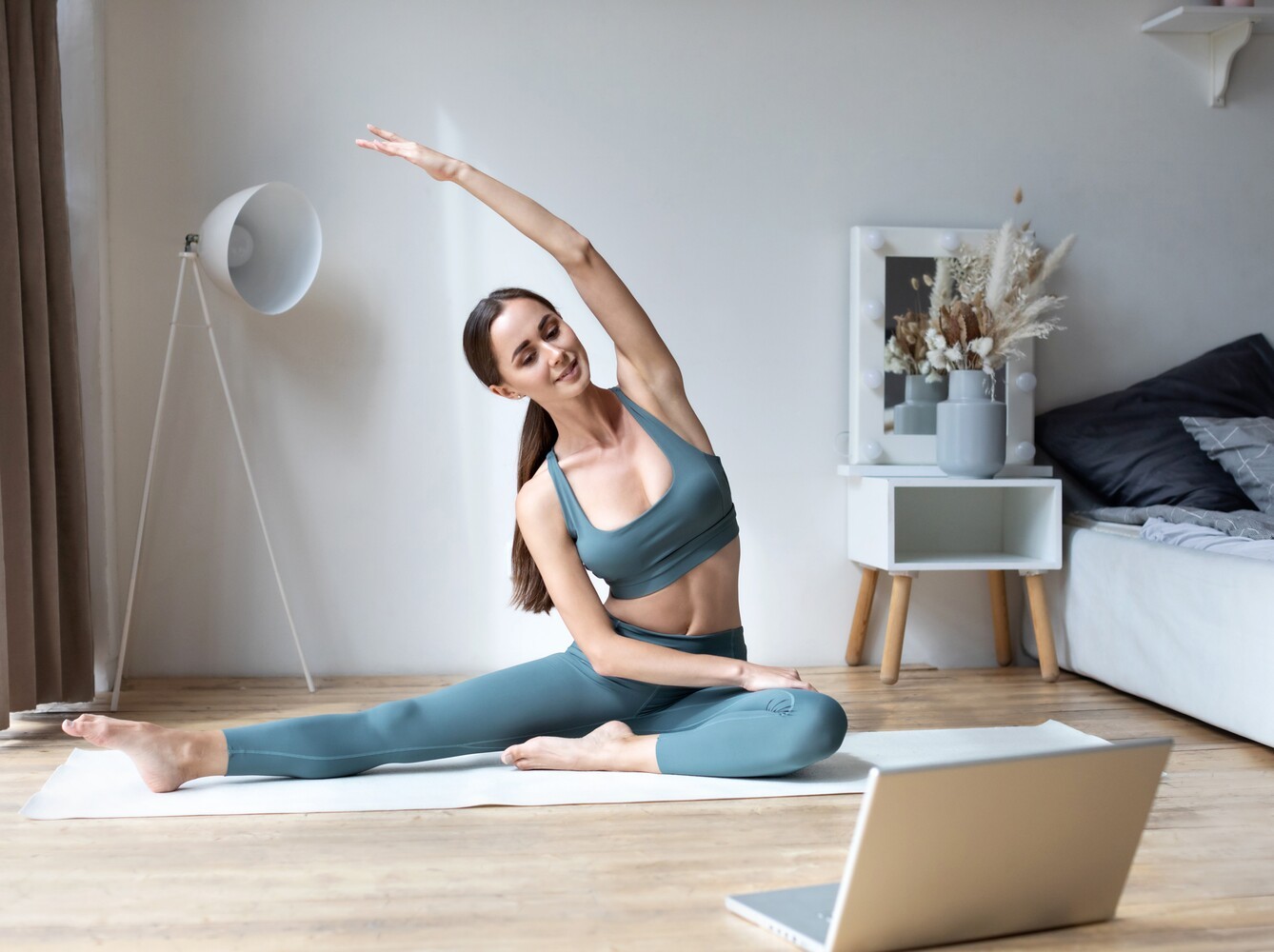 woman following online yoga classes for weight loss on her laptop from the comfort of her living room