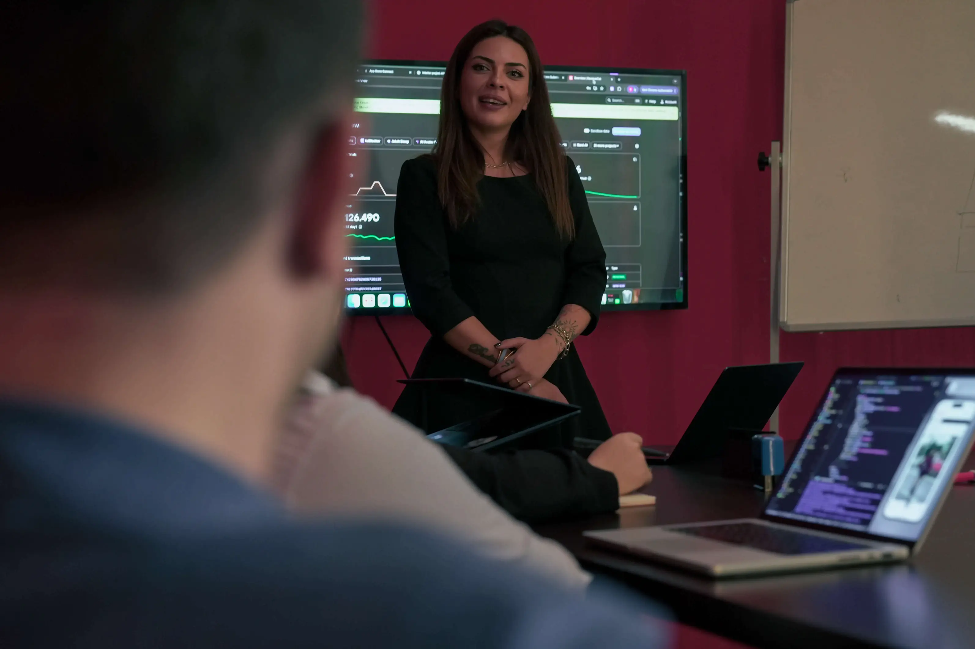 Neon Apps team leader presenting to the team in a meeting room with analytics displayed on a screen.