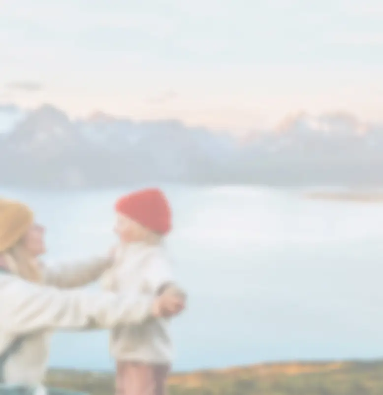 Mother and daughter outdoors, hiking near a large lake with mountains in the background.