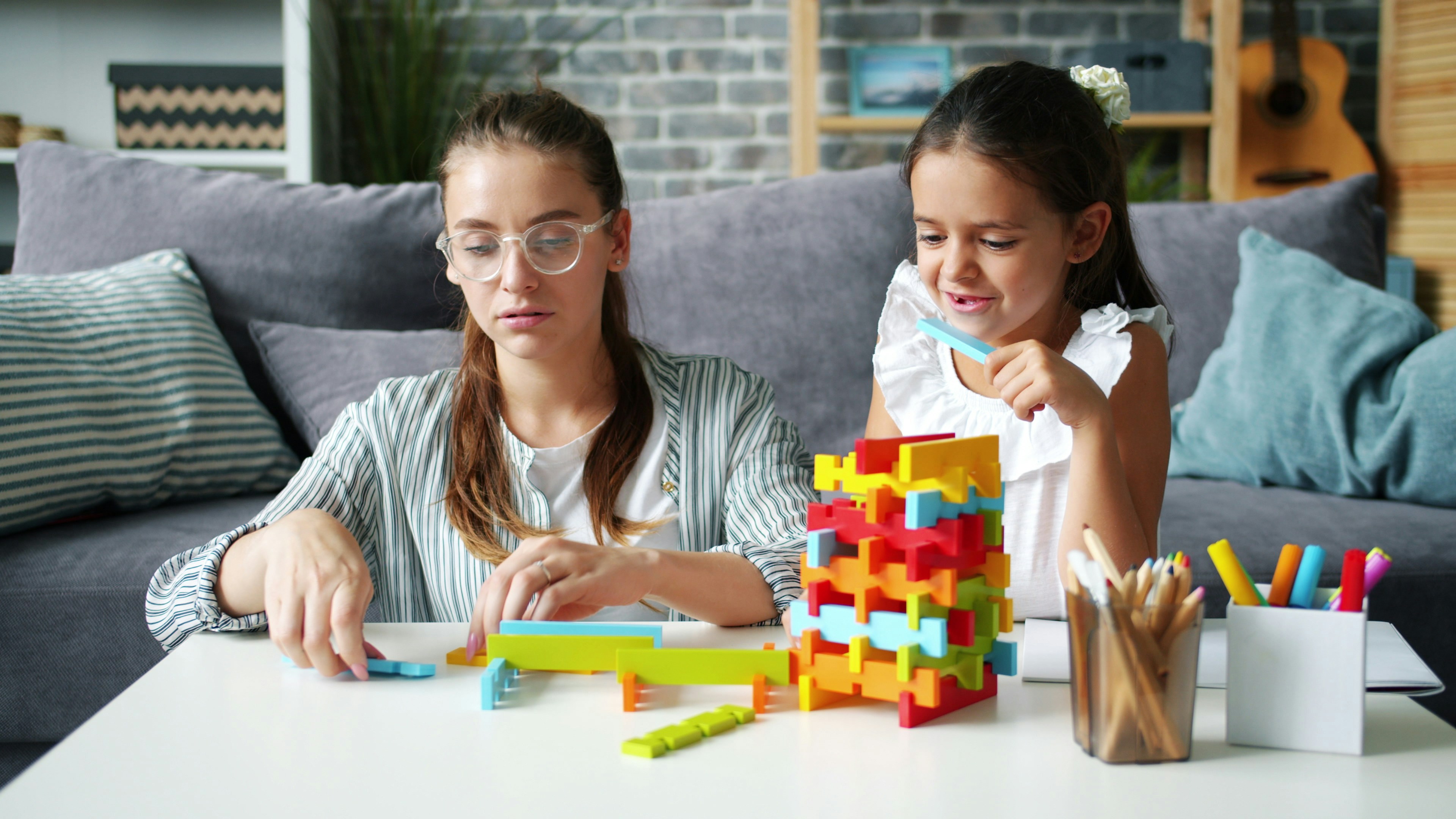 Two girls building with colorful blocks at a table.