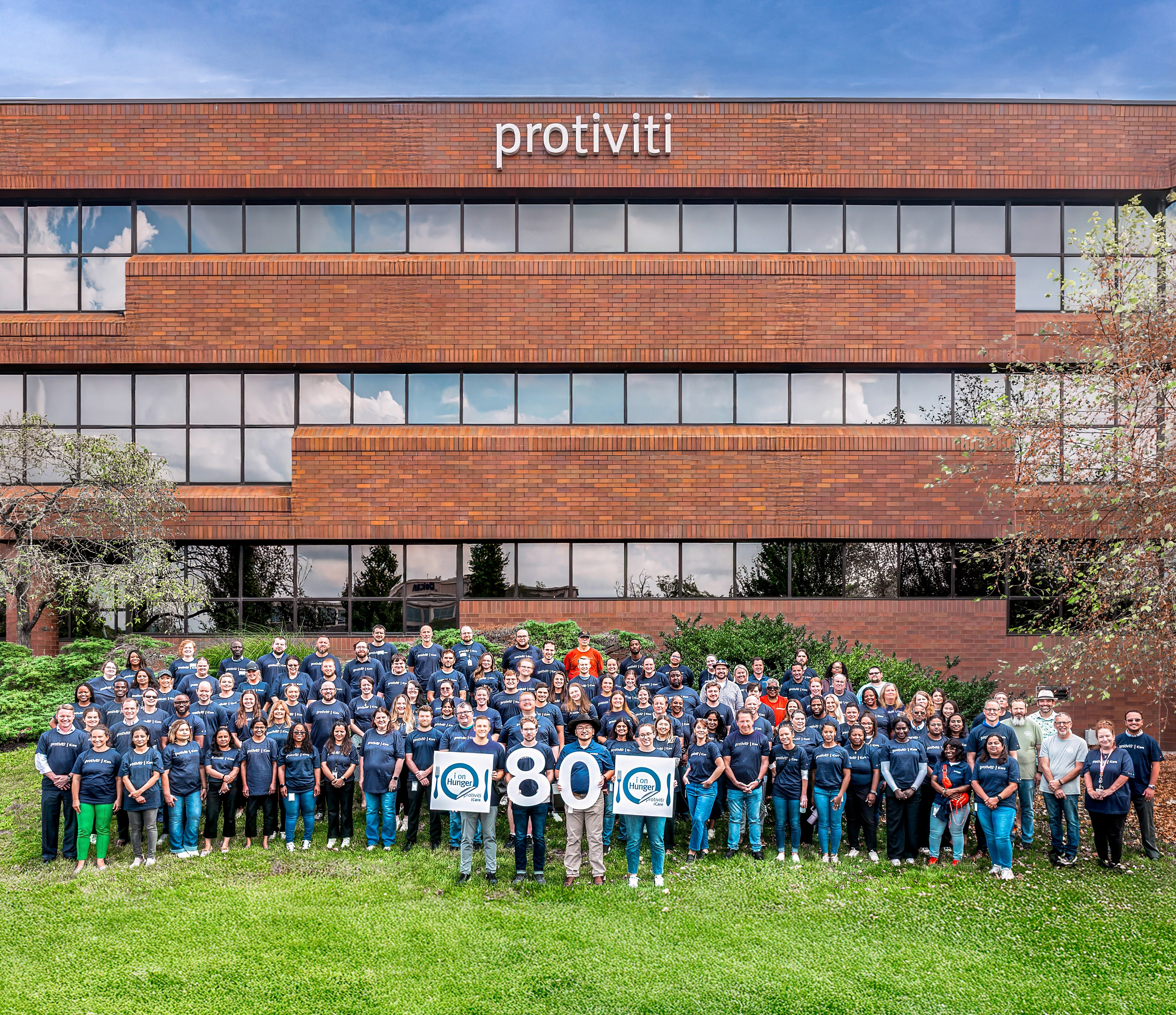 Two workers installing solar panels on a metal frame structure as part of a nonprofit project, outdoors under a partly cloudy sky