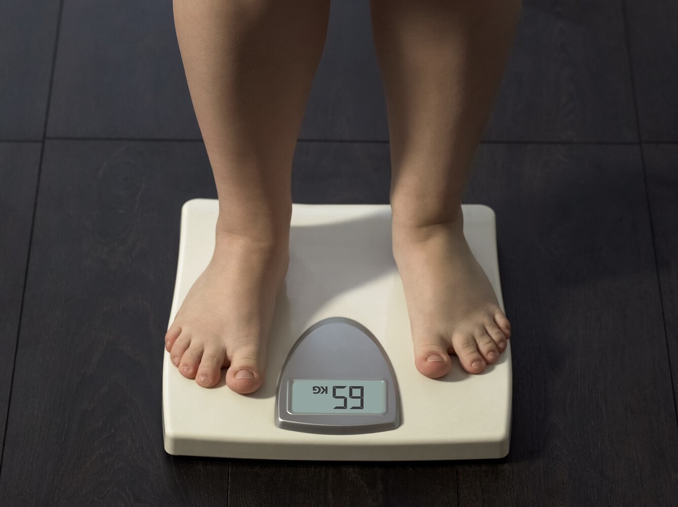 woman standing on a scale in her bathroom to check her results after walking 5 miles a day for weight loss