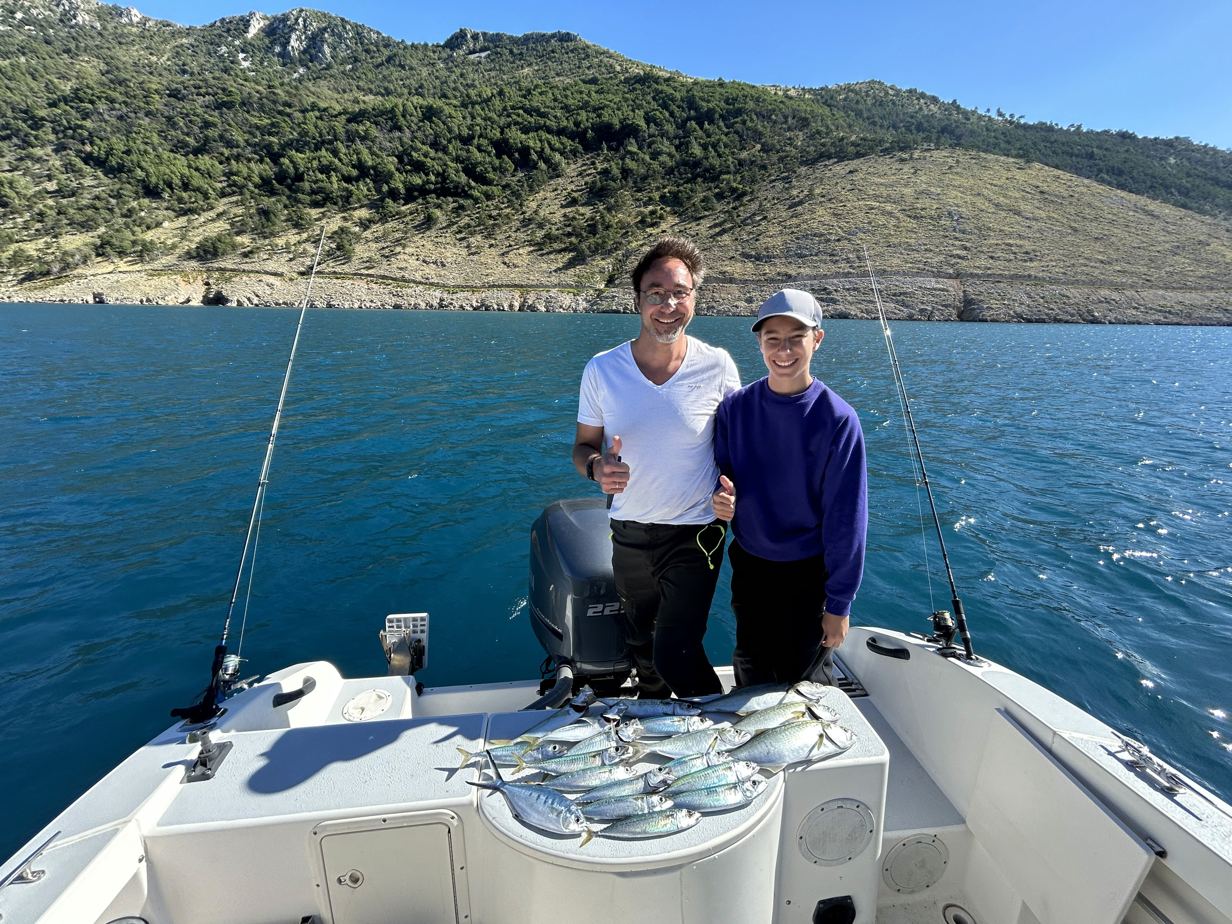 Father and son proudly displaying freshly caught fish during a family fishing trip on the Adriatic Sea.