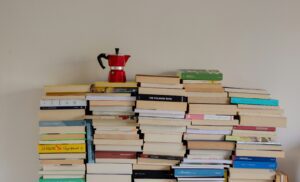Stacks of books with a caffe pot on top.