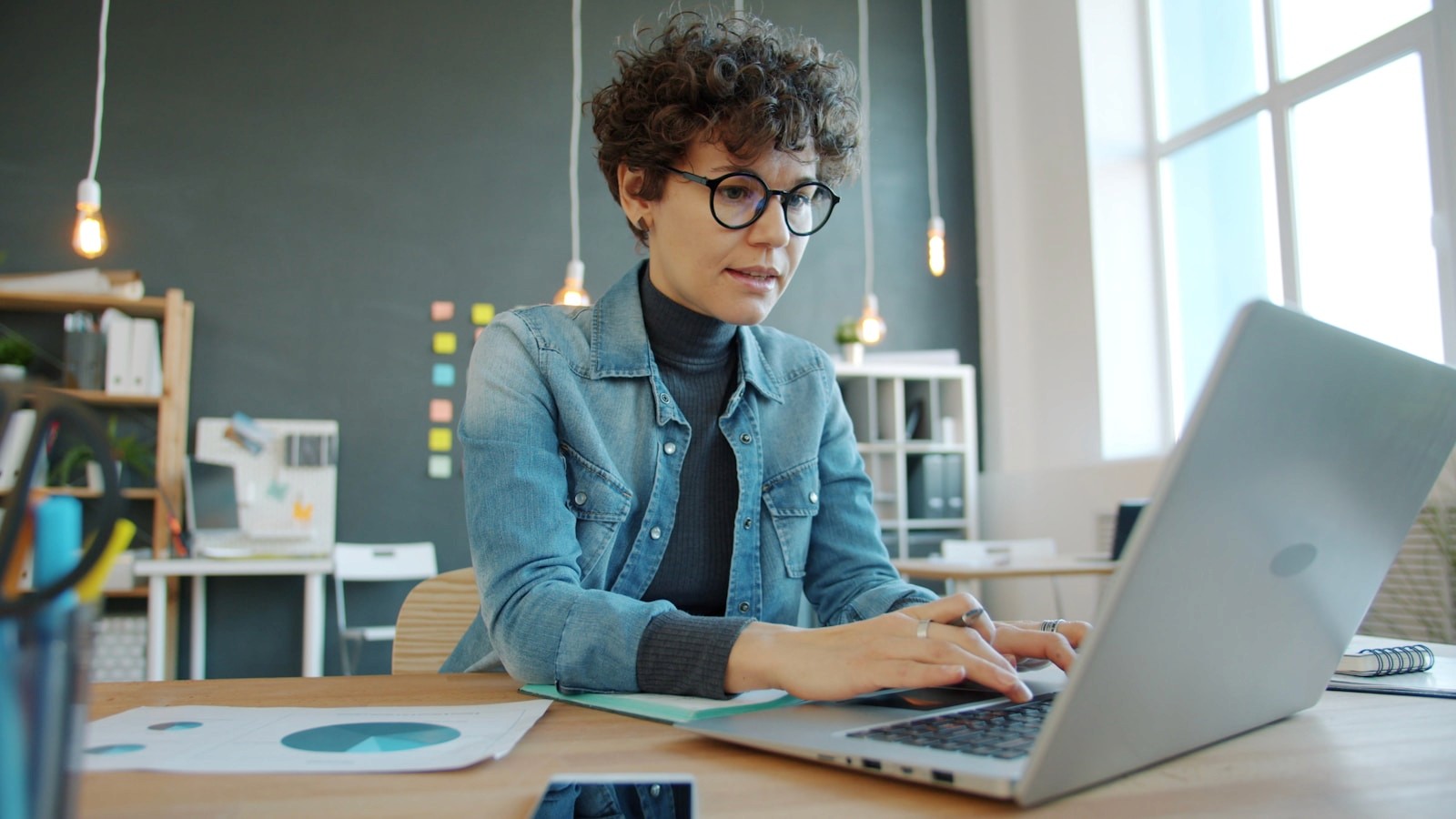 Designer building a portfolio website layout on a laptop in a bright studio