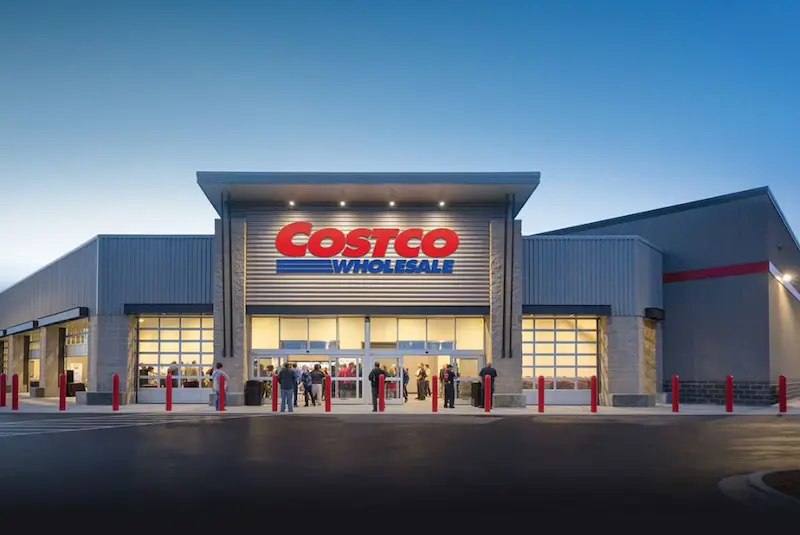Modern Costco Wholesale storefront at dusk, highlighting the bustling entrance and the company's strong brand presence.
