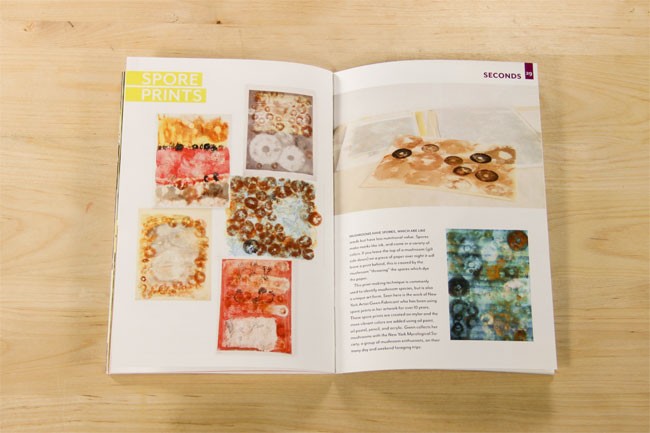 An open book displays two pages. The left page features the title "SPORE PRINTS" in yellow text at the top left corner. Below the title are six square images of artworks with varying colors and textures. The right page contains text under the heading "SECONDS 39," followed by two paragraphs of text. The book rests on a light wooden surface.