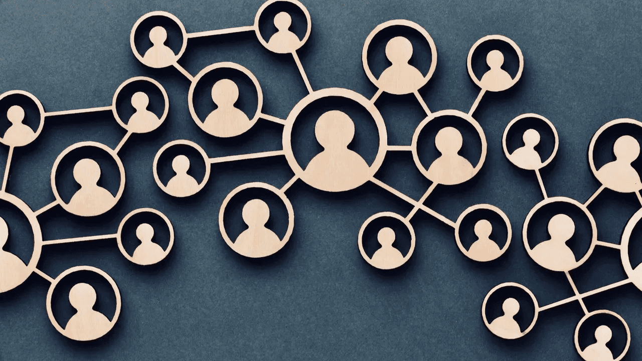 Wooden network of interconnected human icons on a dark background, symbolizing collaboration, communication, and organizational structure.