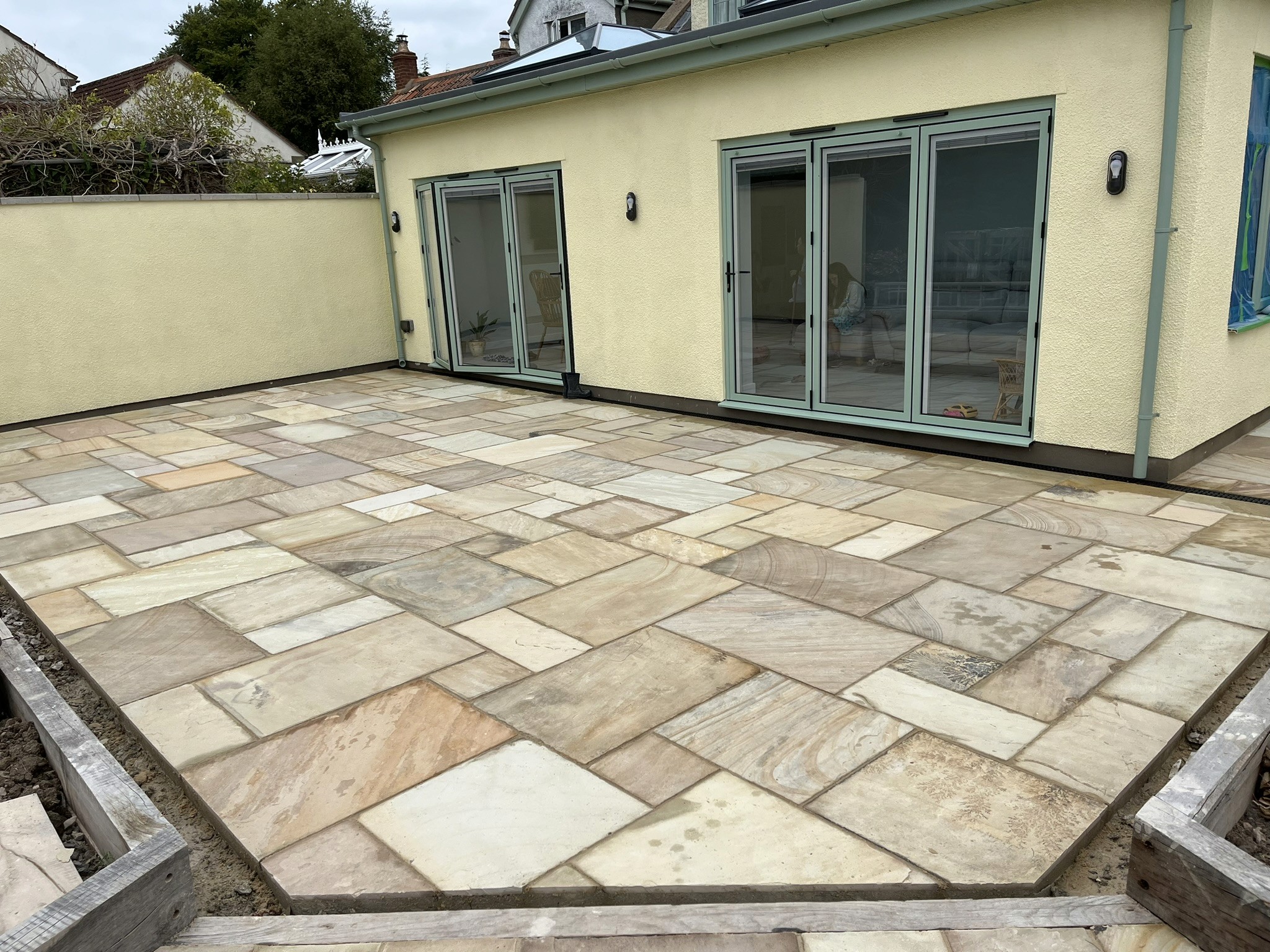 Patio with rectangular natural stone slabs in varied beige and grey tones outside wide glass doors.
