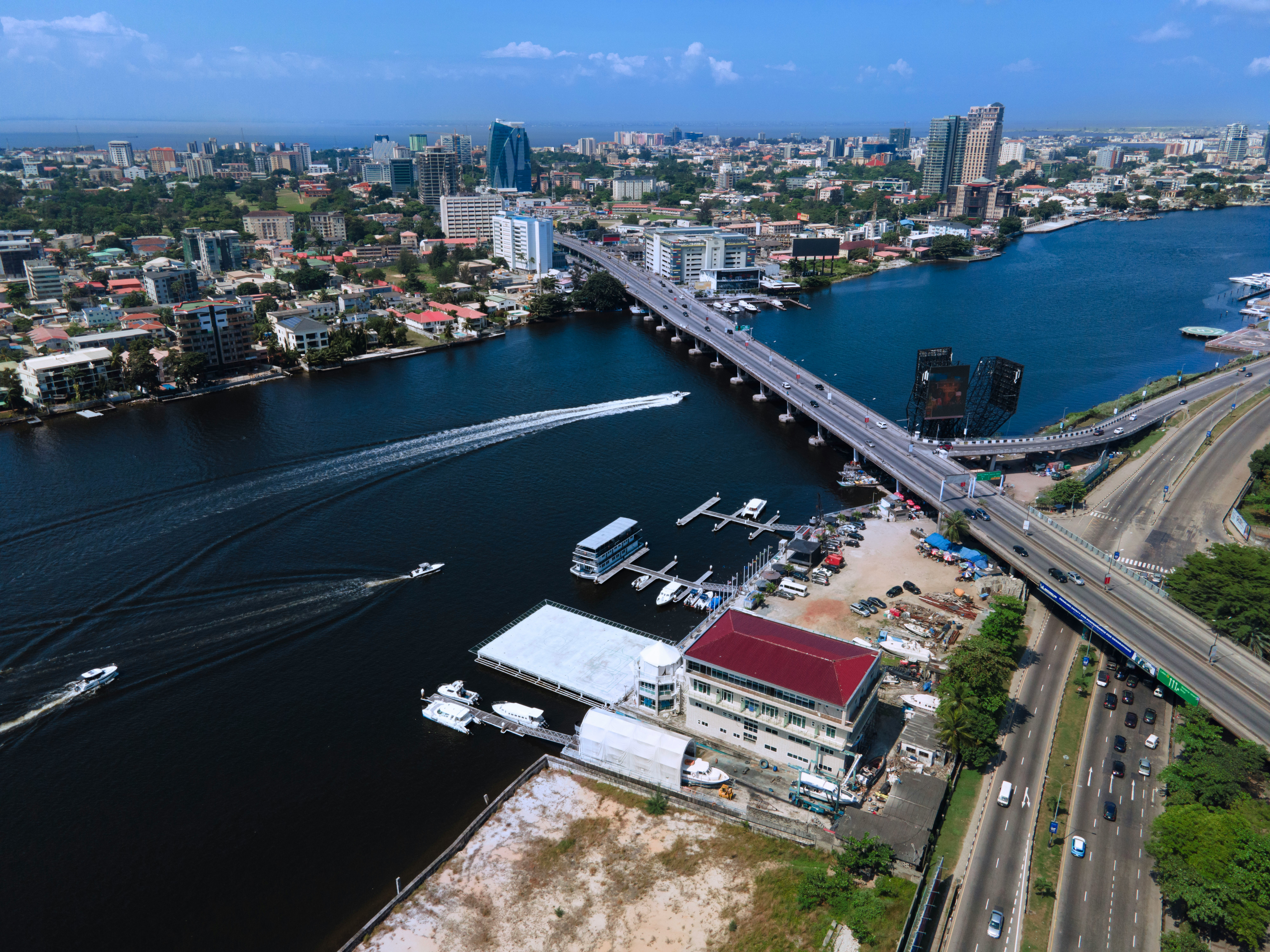 Boats navigate a wide river beside a modern city bridge.