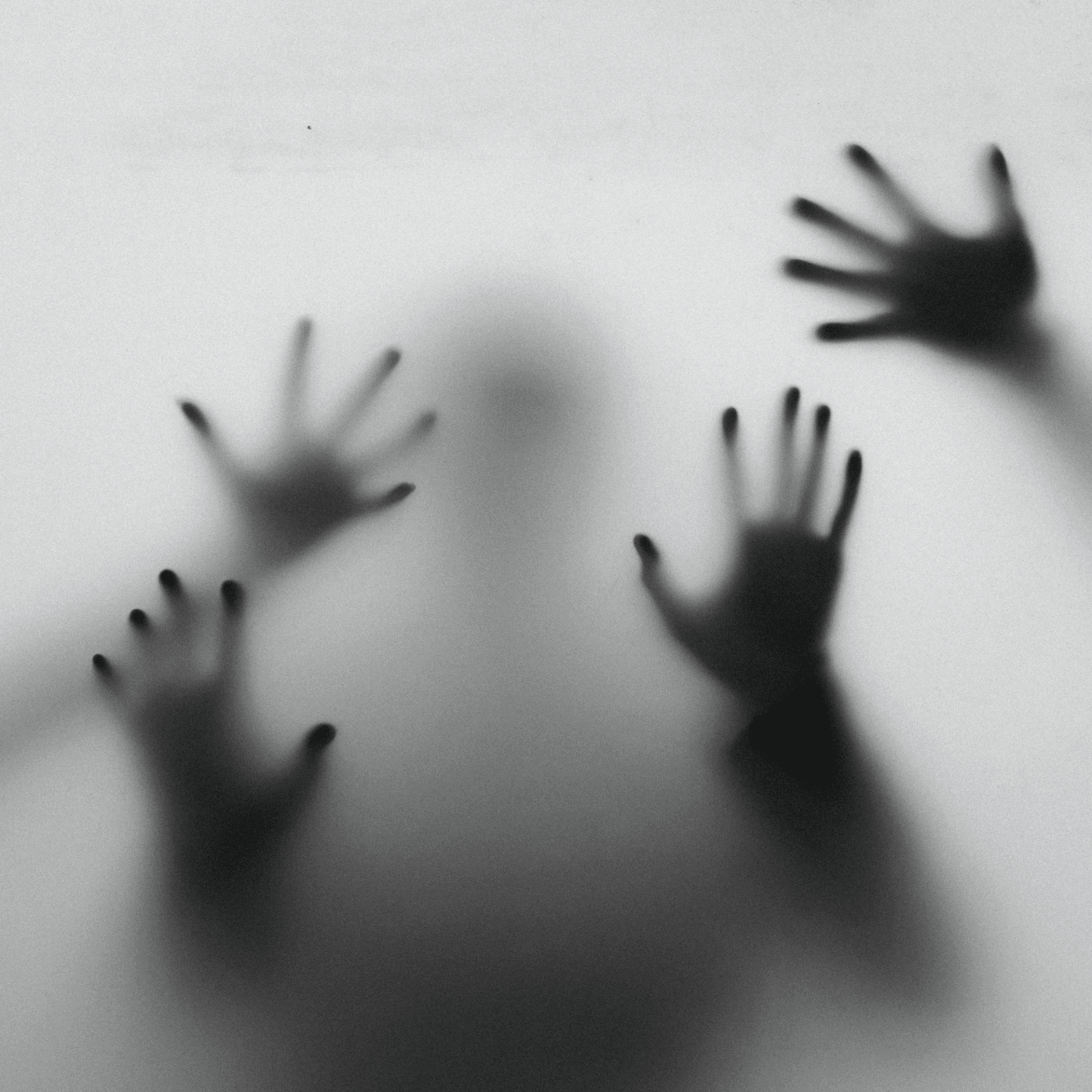 A black and white photograph showing four hands pressed against frosted glass, with a person's figure distantly visible in the center of the image behind the glass.